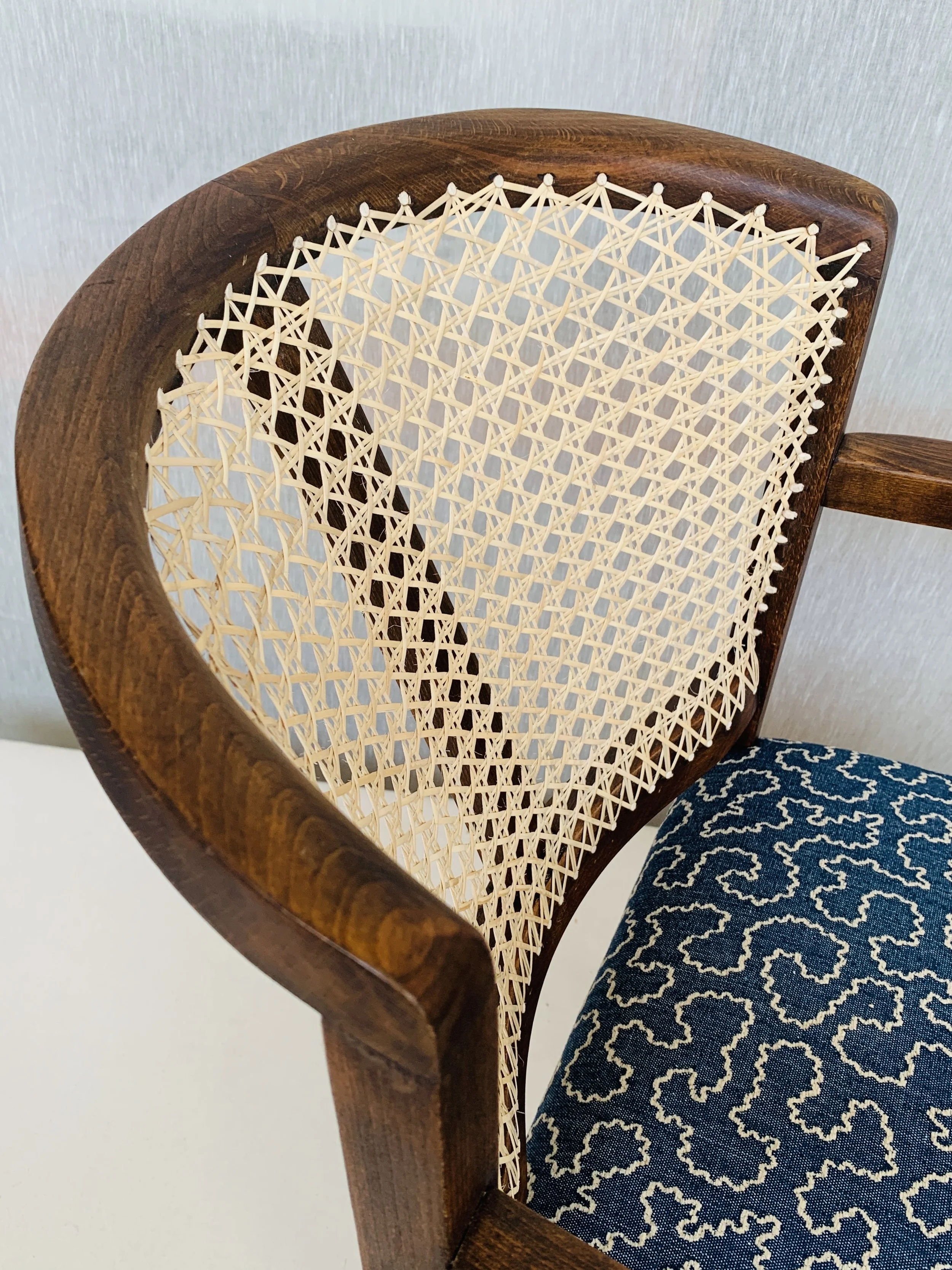 Wooden chair with woven cane backrest and cushioned seat with blue and white pattern.