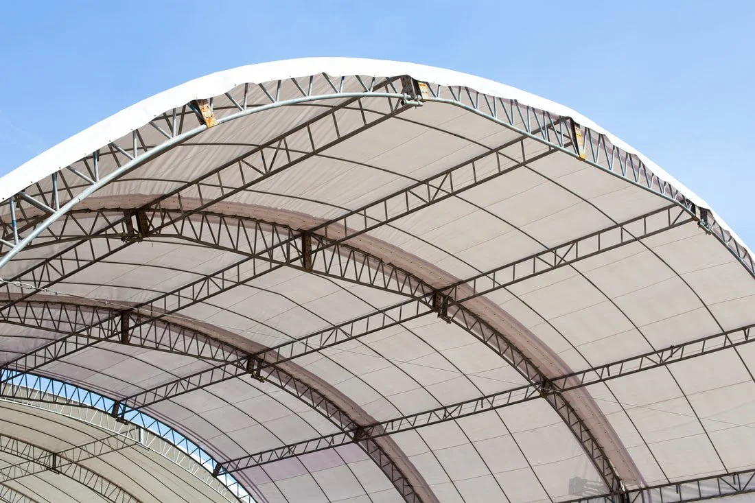 Detail of arched steel truss system supporting the fabric membrane, illustrating load transfer, connection design, and stiffness requirements for long-span applications.