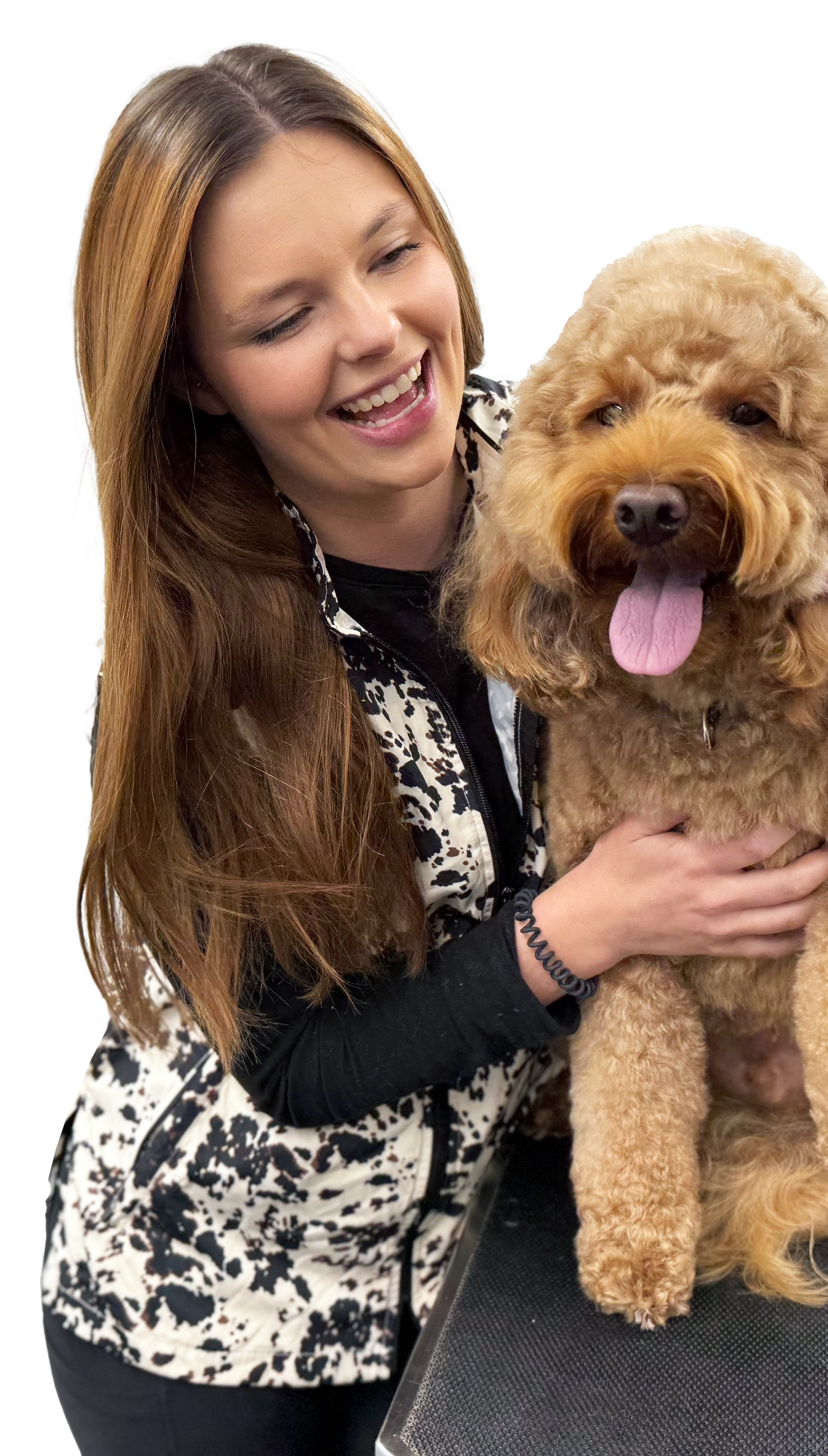 A woman with long brown hair smiling and holding a fluffy, curly-haired brown dog with its tongue out.