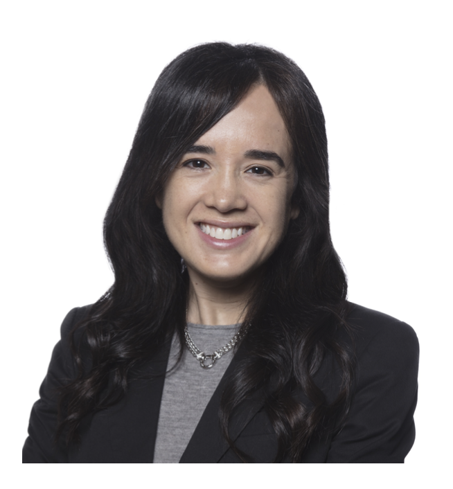 Professional woman with long dark hair smiling, wearing a blazer and necklace against a white background.