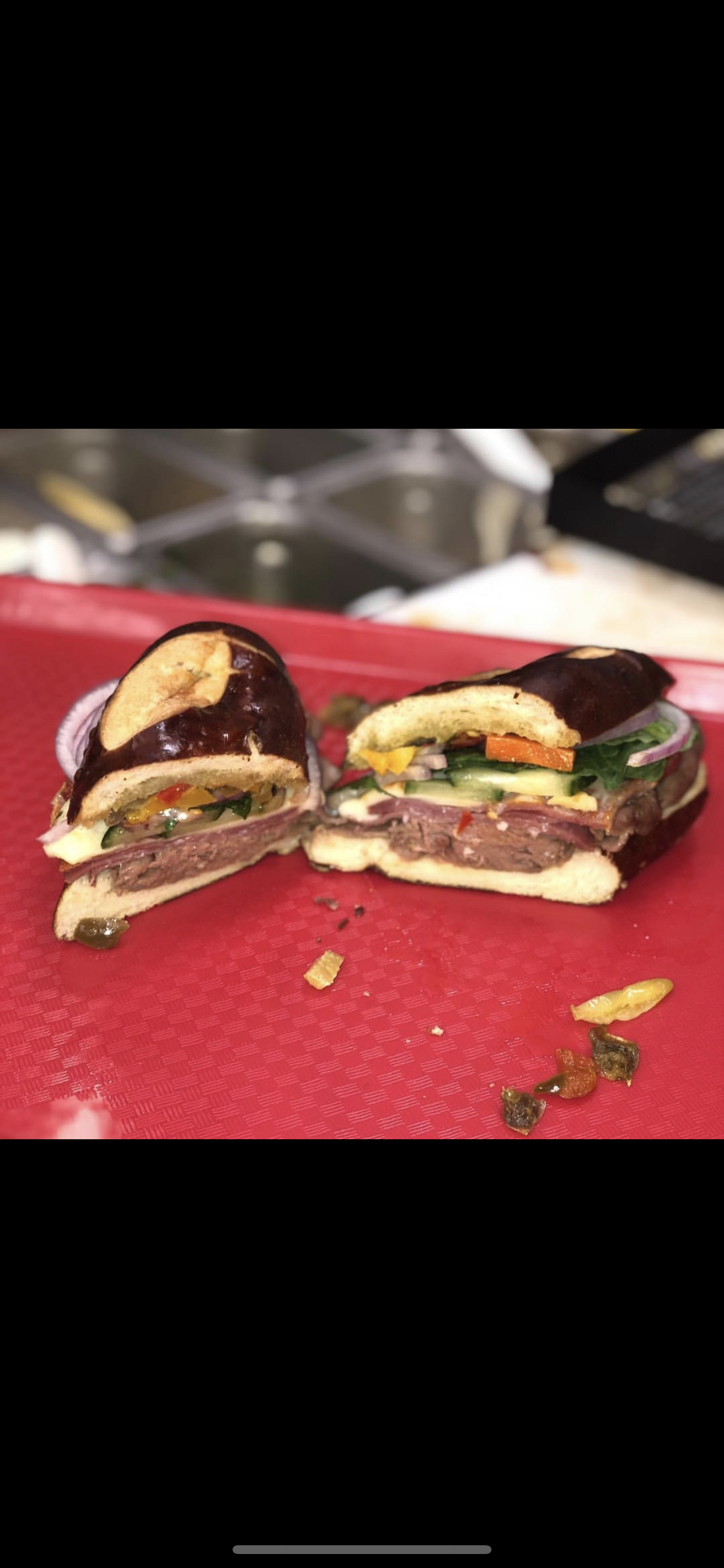 Half of a sandwich with roast beef, vegetables, lettuce, and sauce on a red platter.
