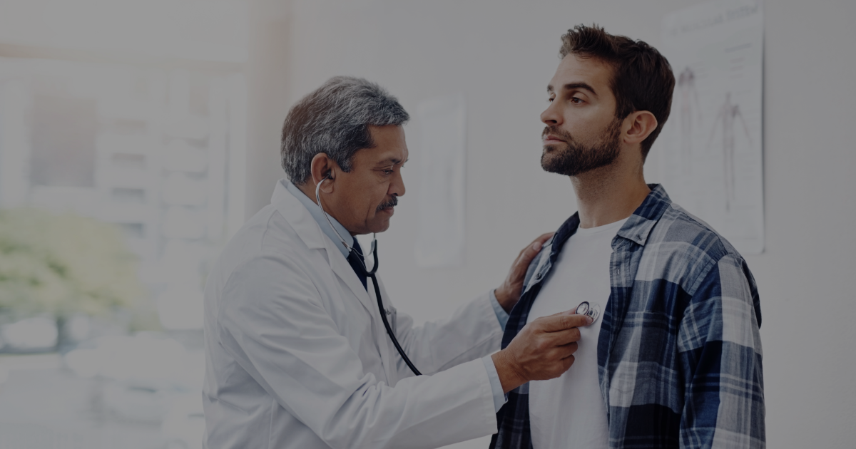 Doctor using a stethoscope on a young man in a medical office.