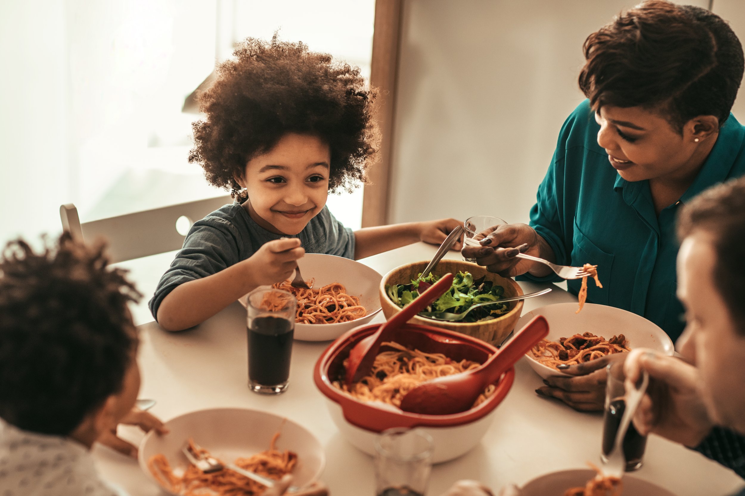 Family sharing a meal at the dining table, with pasta and salad.