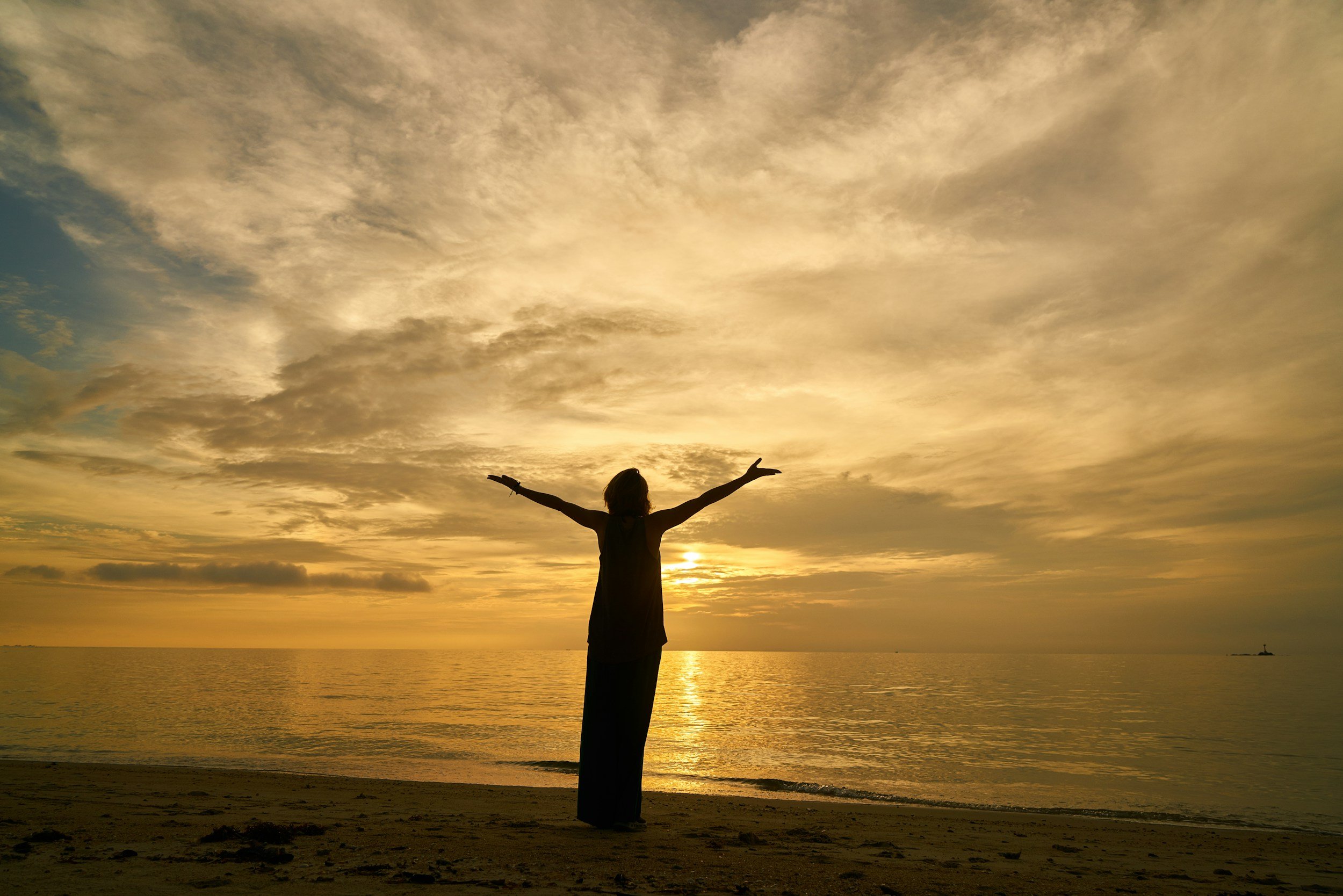 Person standing on beach at sunset symbolizing hope, healing, and faith-based support through Christian counseling at Heartland Counseling and Wellness