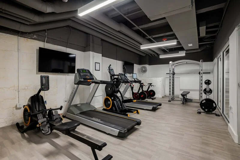 Interior of a modern gym with cardio machines, strength training equipment, and mirrors.