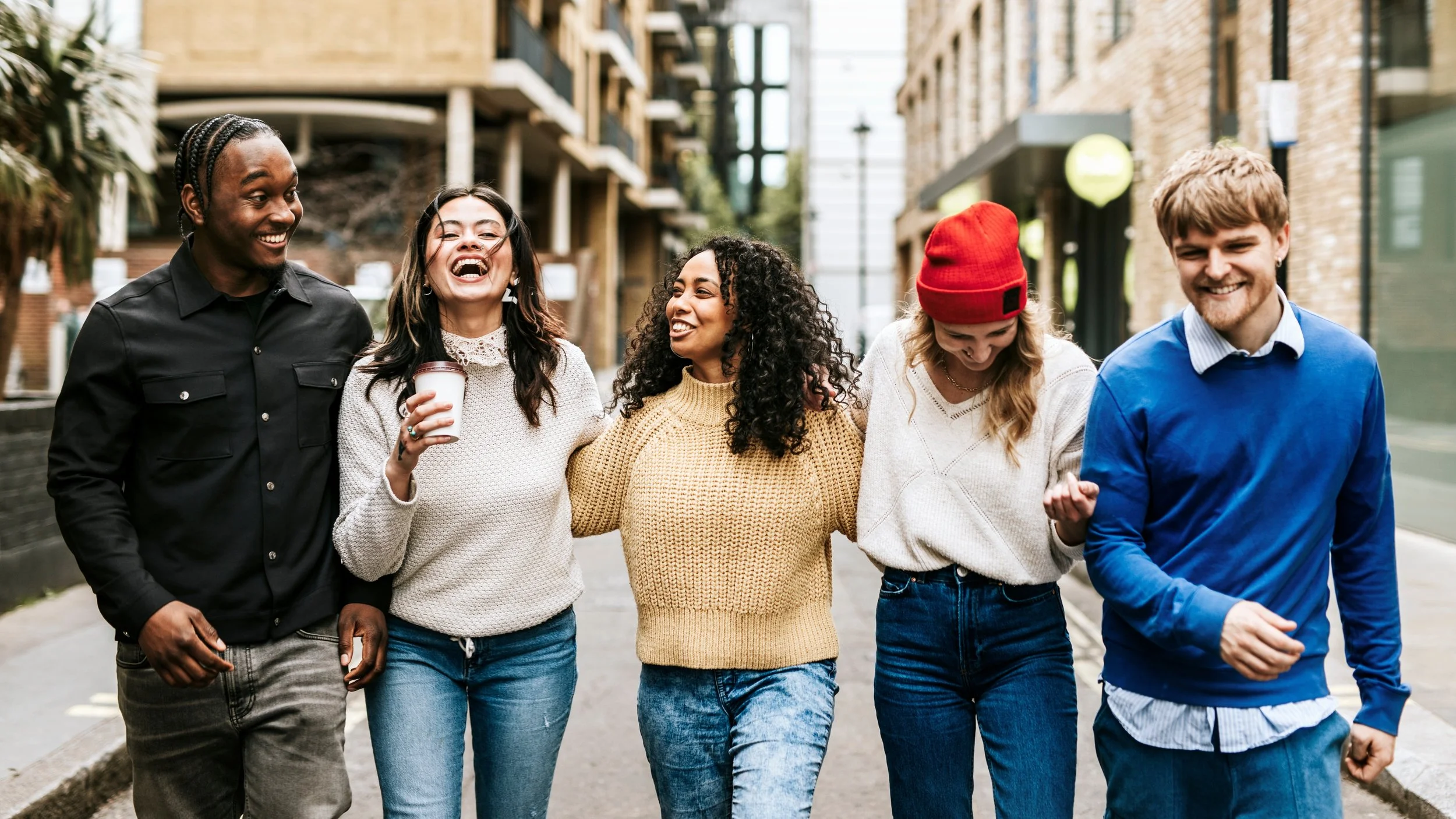 Group of five diverse friends walking together outdoors and enjoying each other's company.