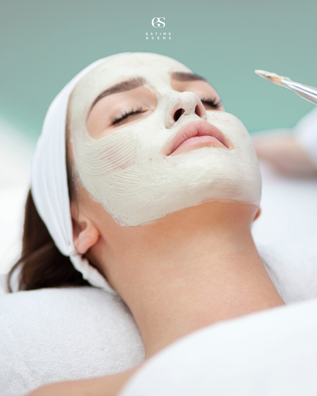 Femme recevant un soin du visage avec un masque facial, allongée avec les yeux fermés.