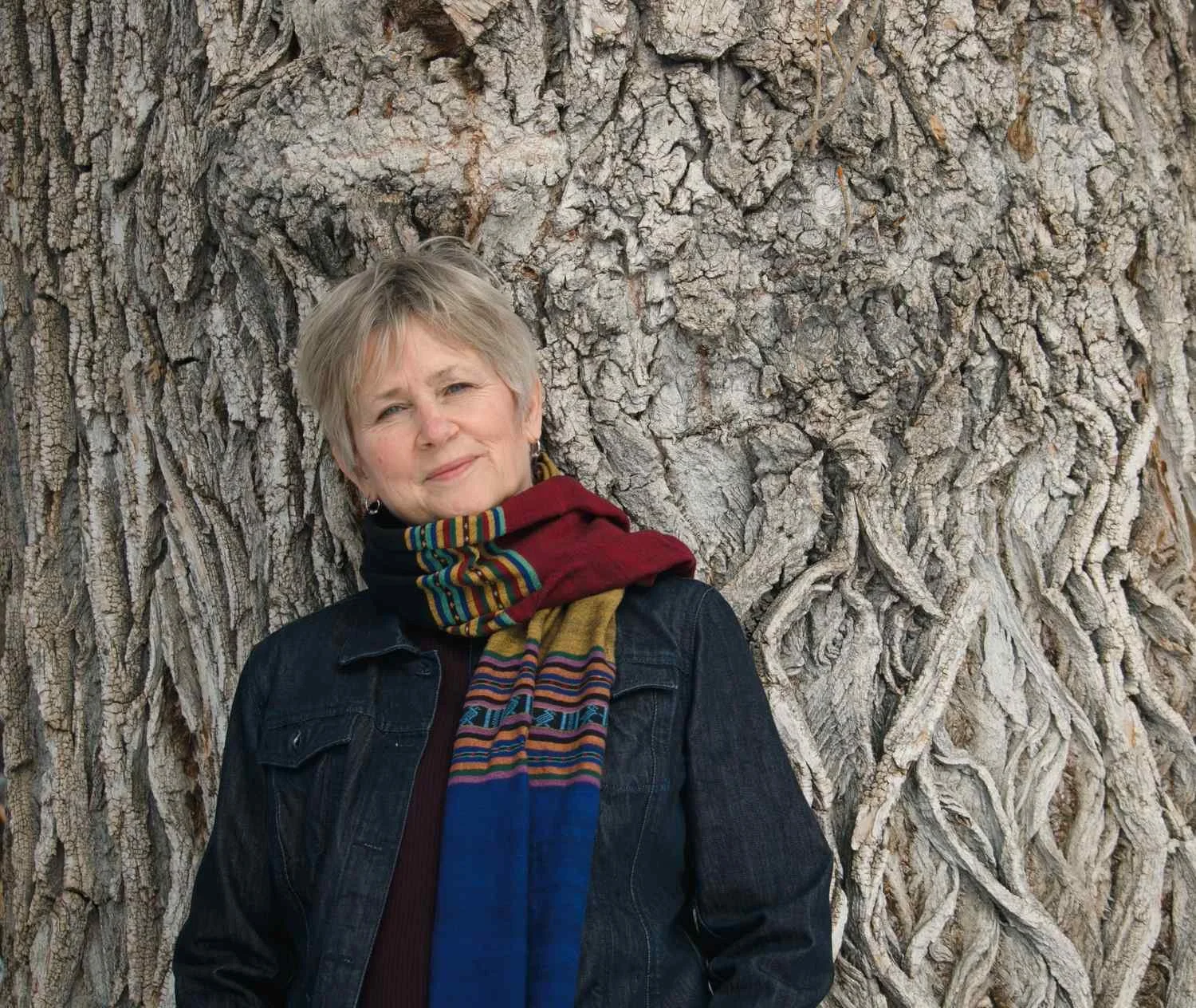 Close-up portrait of Liz Rees resting peacefully against a gnarled tree trunk