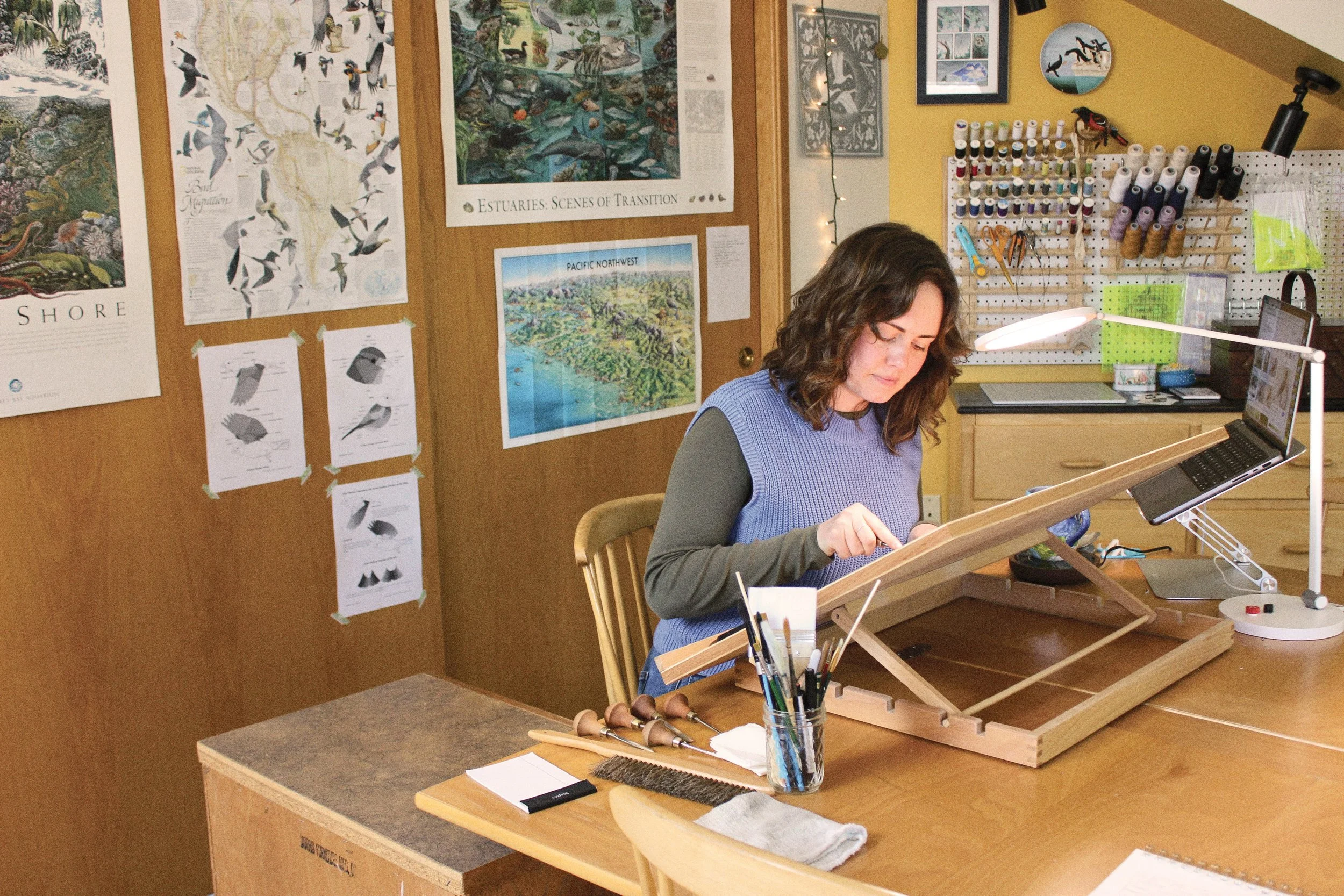 Nyssa sits at her desk and works on a project in her studio