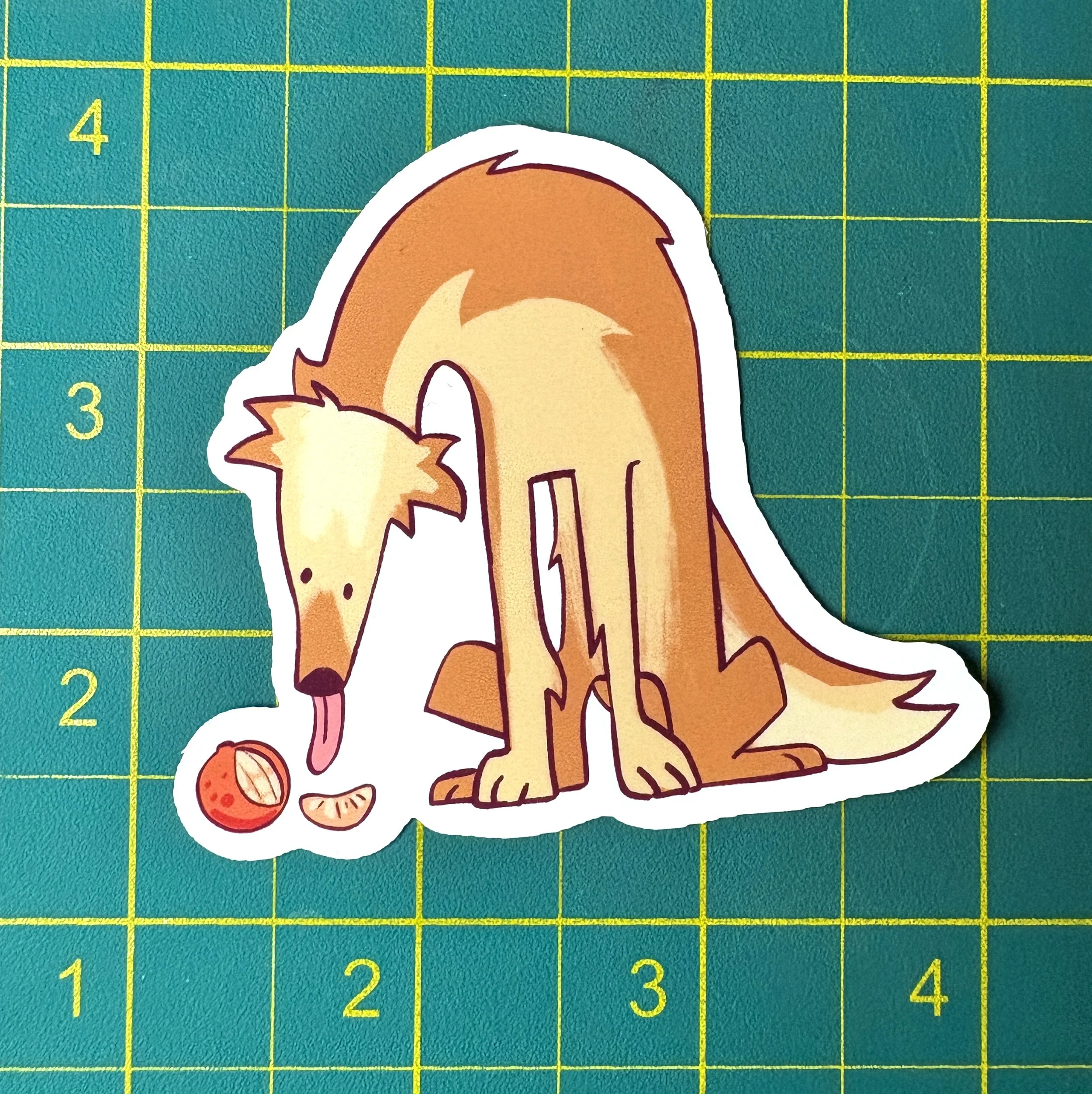 Sticker of a cartoon dog placed on a green cutting mat with yellow grid lines numbered along the edges.