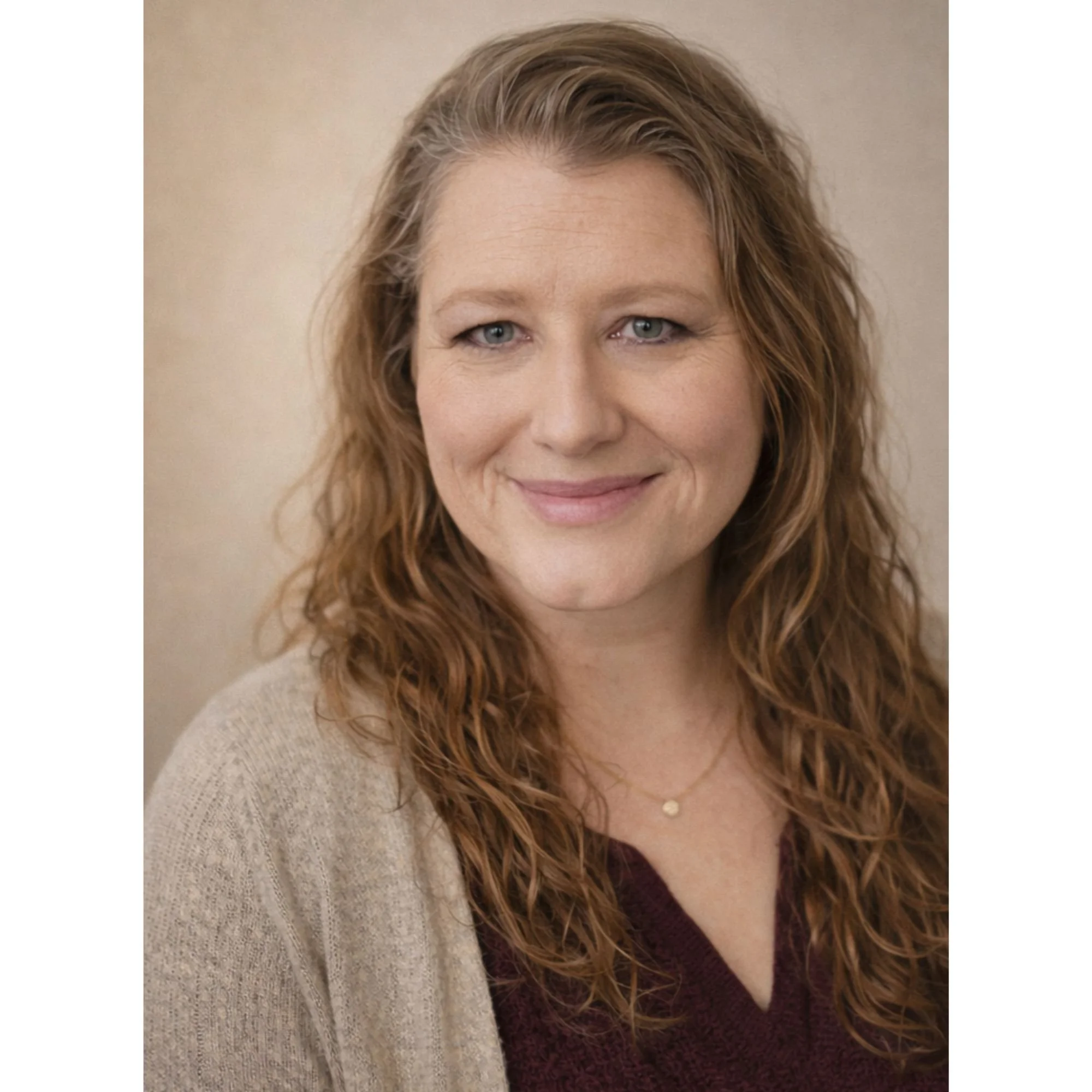 Close-up of a woman's face with wavy, brown hair, wearing a beige sweater and a burgundy top, smiling softly. Telehealth Psychotherapist, Indiana Accepting Aetna, Anthem Blue Cross Blue Shield, and Carelon.