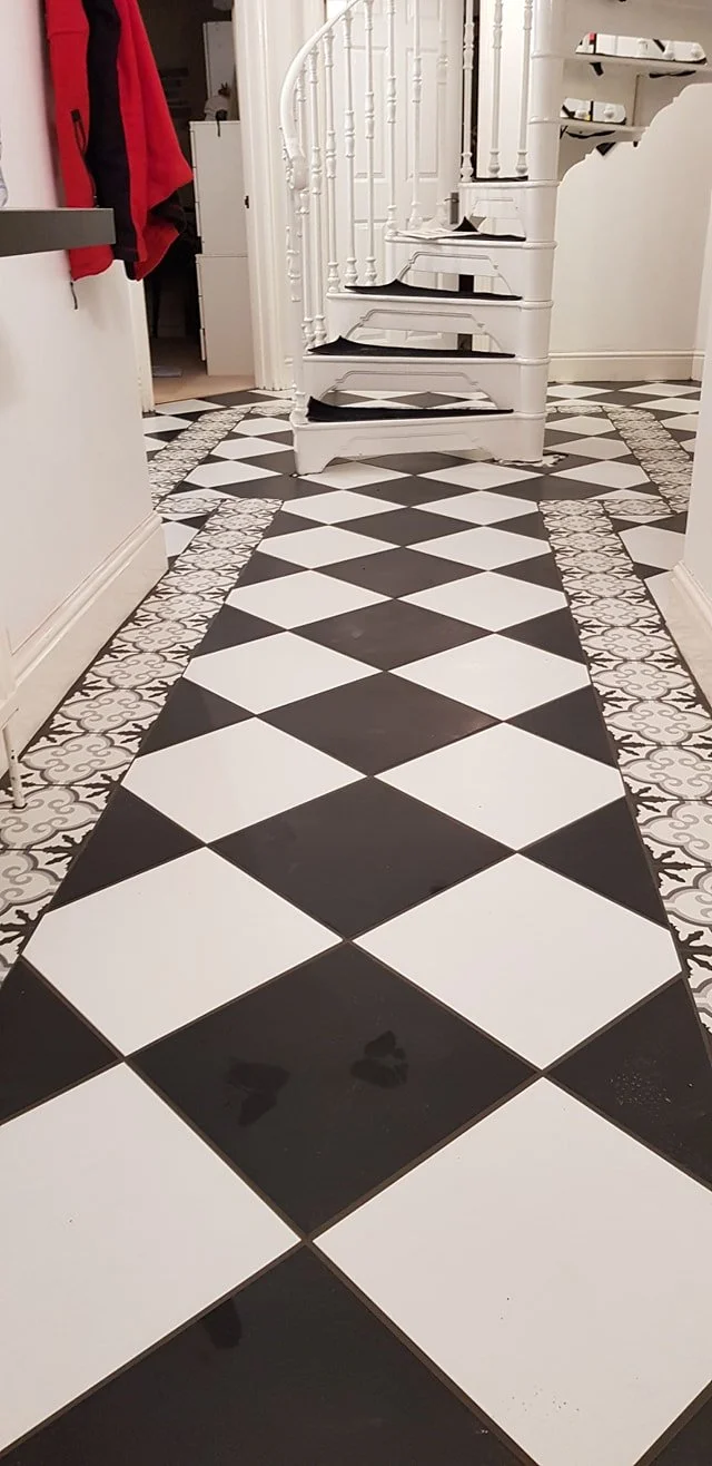 Black and white checkered tile floor leading to a white spiral staircase in a home interior.