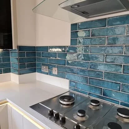Kitchen countertop with a stove and a blue tile backsplash.
