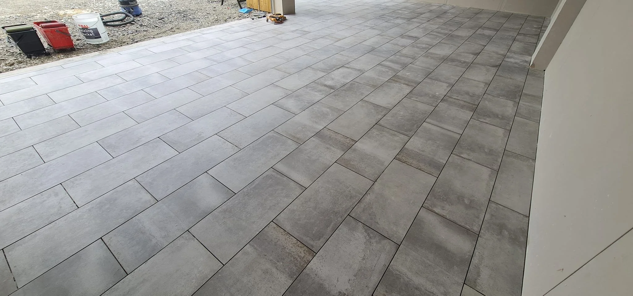 A newly installed exterior concrete porch with light gray and darker gray tiles arranged in a pattern.