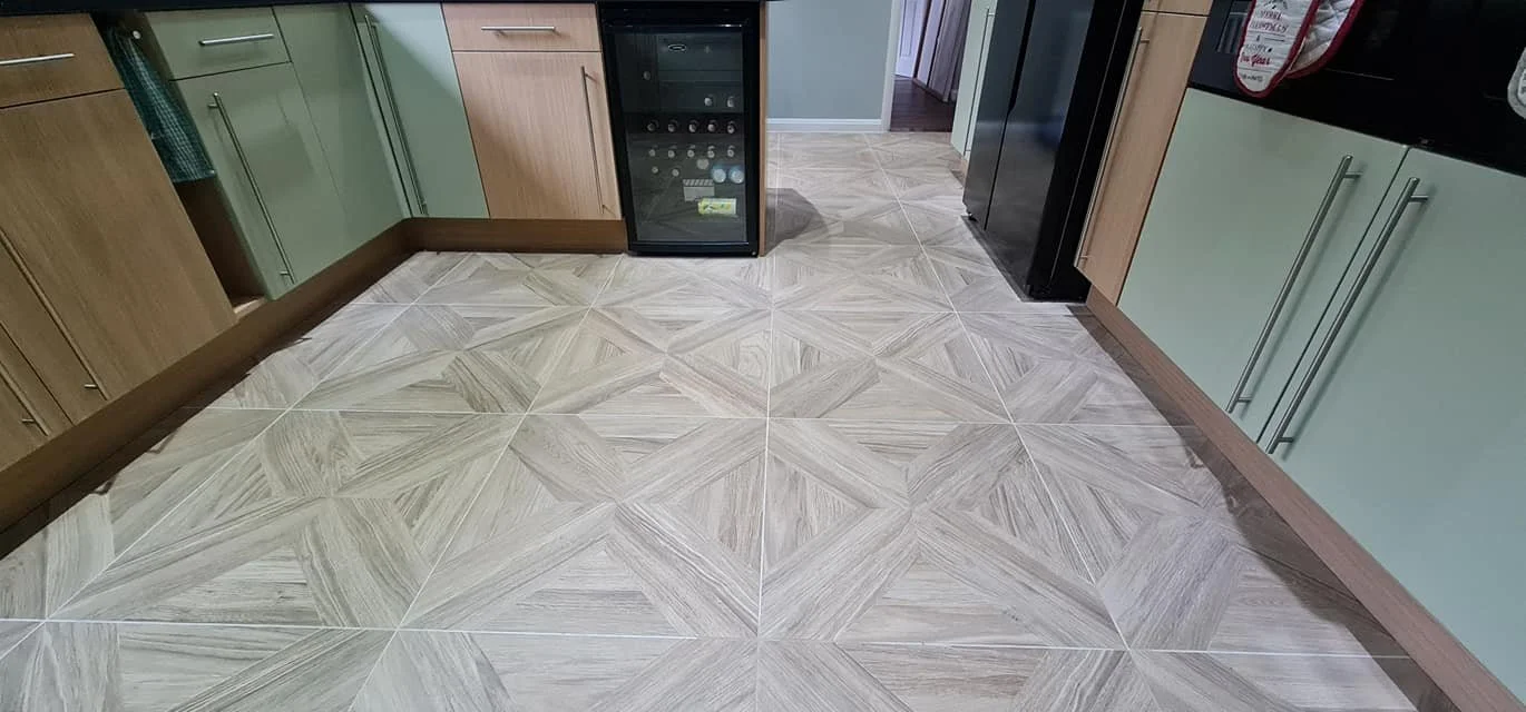 View of kitchen floor with patterned tiles, wooden and green cabinets, and a wine cooler.