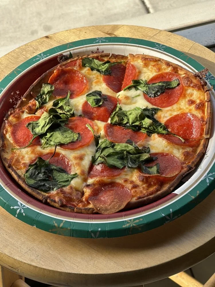 Half a pepperoni and spinach pizza on a festive paper plate.