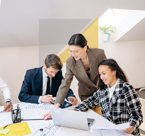 Personas en una reunión de trabajo colaborando con una laptop en una oficina moderna