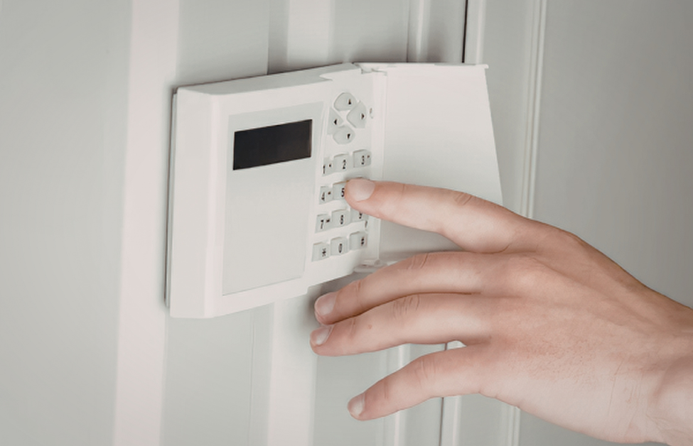 Una mano tocando un panel de control blanco en la pared.