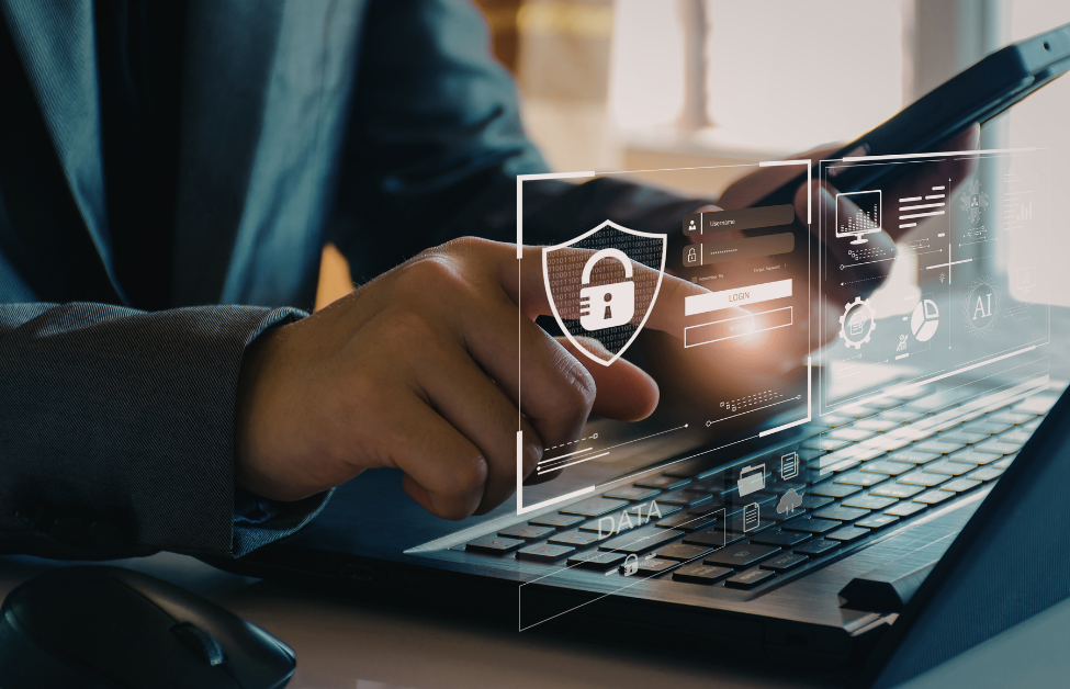 Persona usando un teléfono móvil y una laptop con gráficos y candado de seguridad digital en la pantalla.