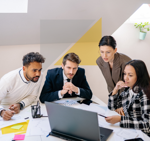 Cuatro personas en una reunión de trabajo frente a una computadora portátil en una oficina moderna