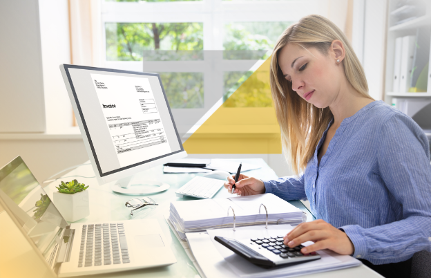 Mujer trabajando en escritorio con computadora, documentos, calculadora y planta en oficina bien iluminada