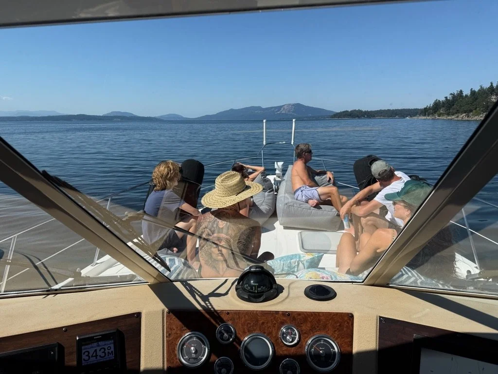 People relaxing on a boat on the water with a scenic view of mountains and the horizon in the background.