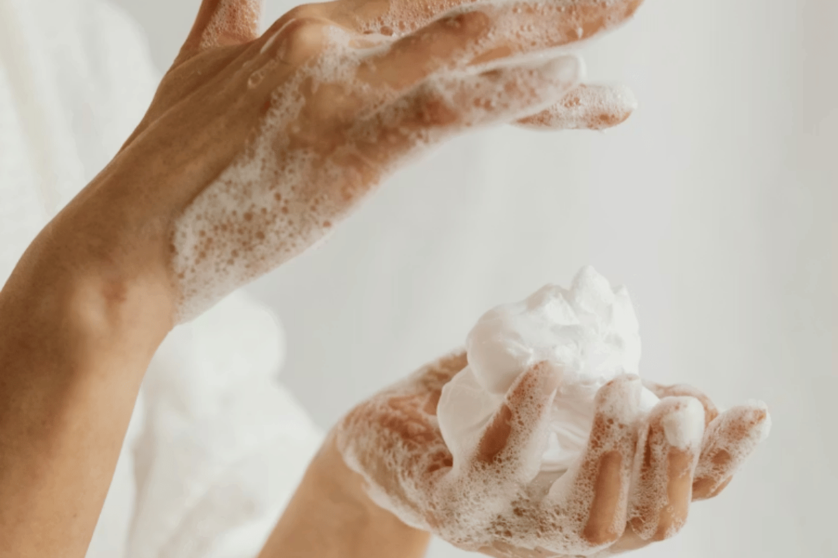 Hands washing with soap and creating lather, with a white background.