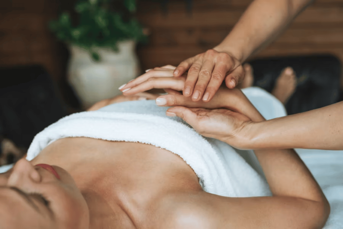 An esthetician holding a clients hand who is on the treatment table, holding space during the service