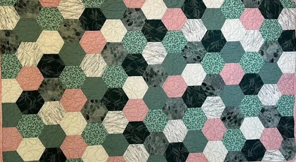 Close-up view of a patchwork quilt made of hexagon fabric pieces in various colors and patterns.