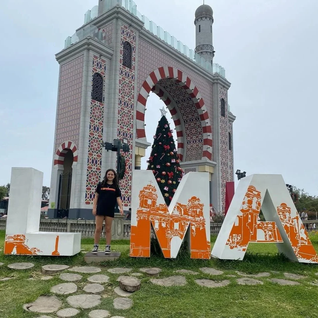 A photo of Yessenia's daughter, Daniela standing in the middle of a LIMA, Peru sign.