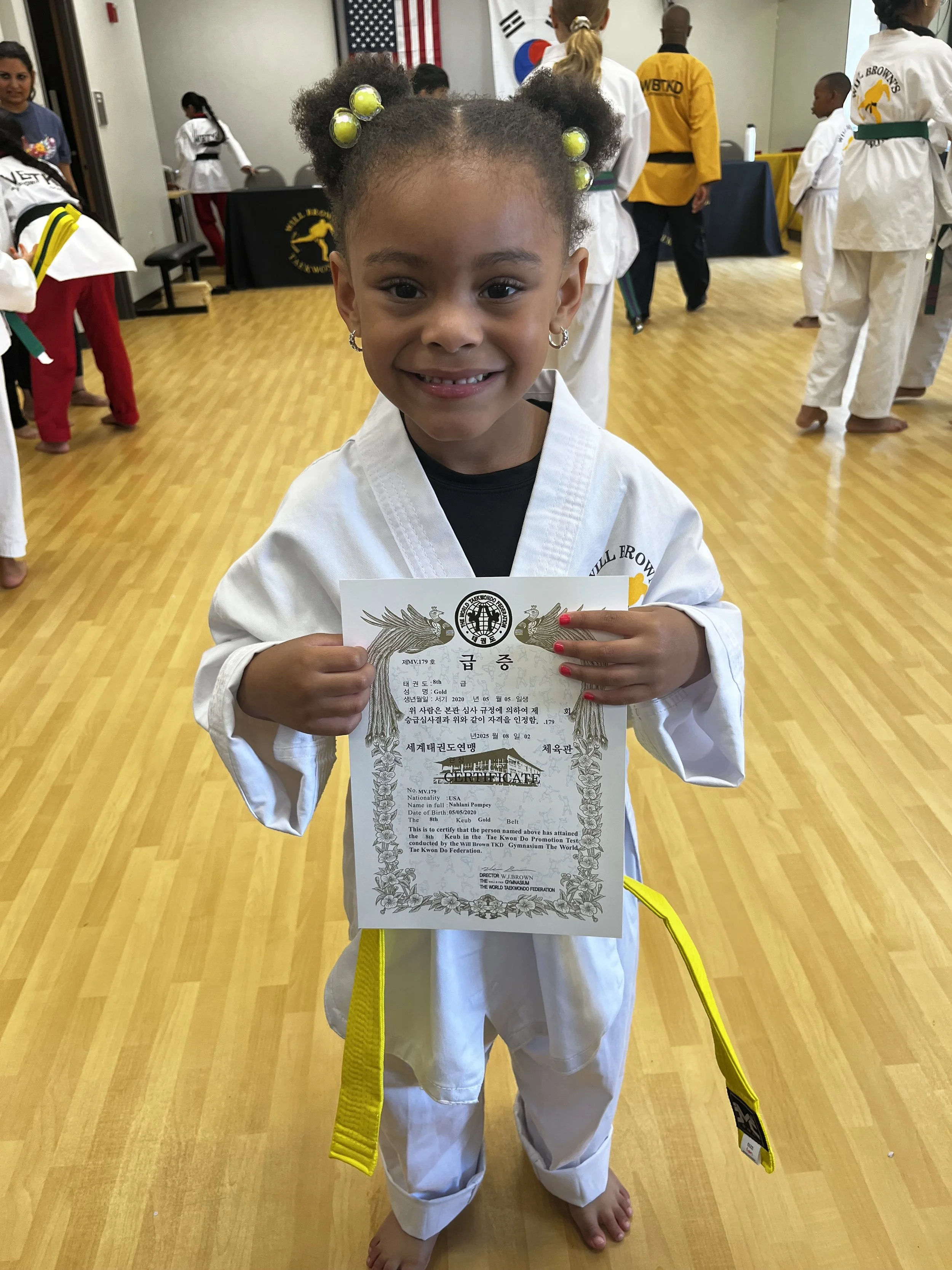 A young student at Will Brown's Taekwondo proudly holding her belt promotion certificate after earning her gold belt.
