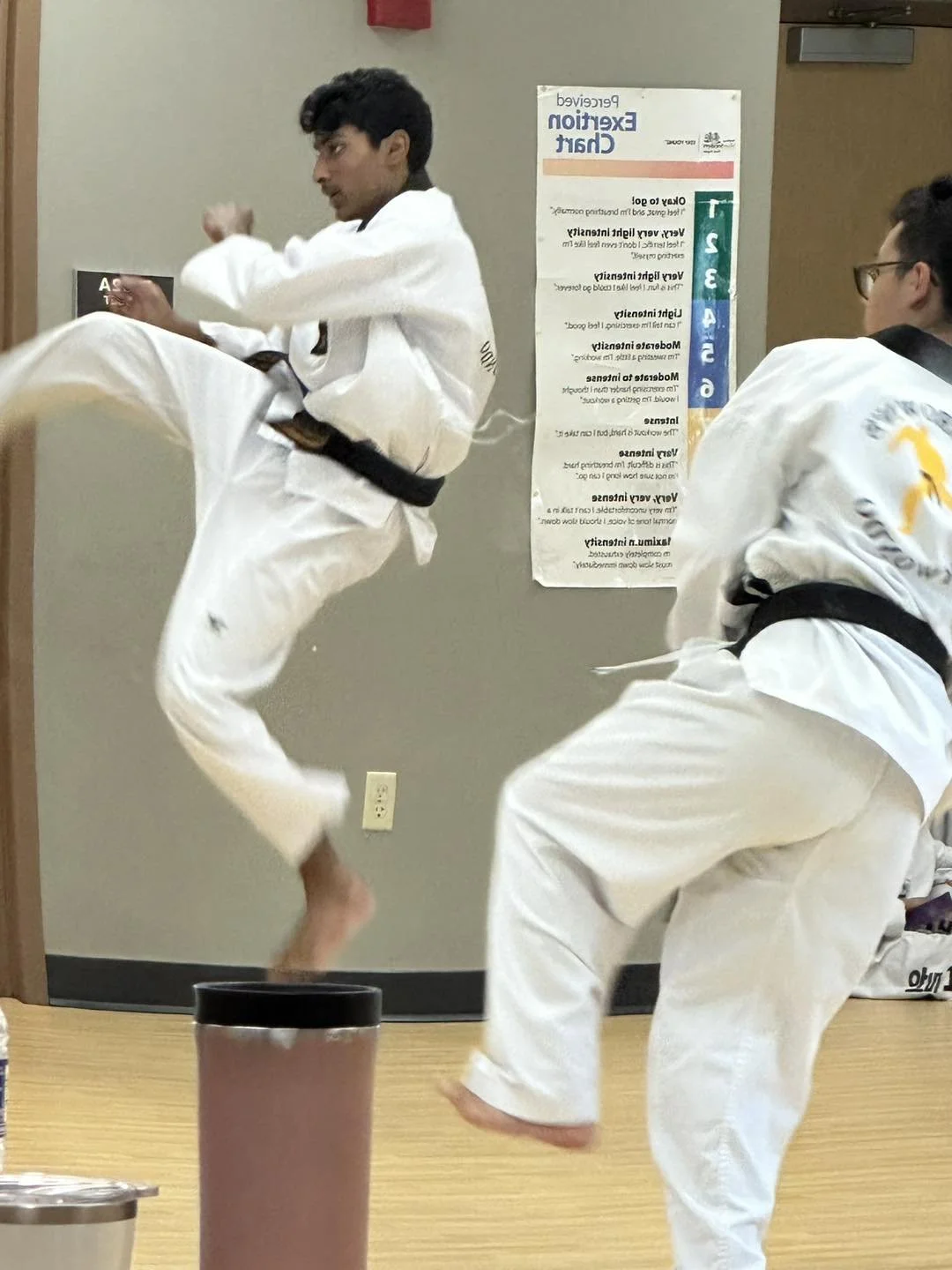 Two students in black belts practicing kicks during a class at Will Brown's Taekwondo.