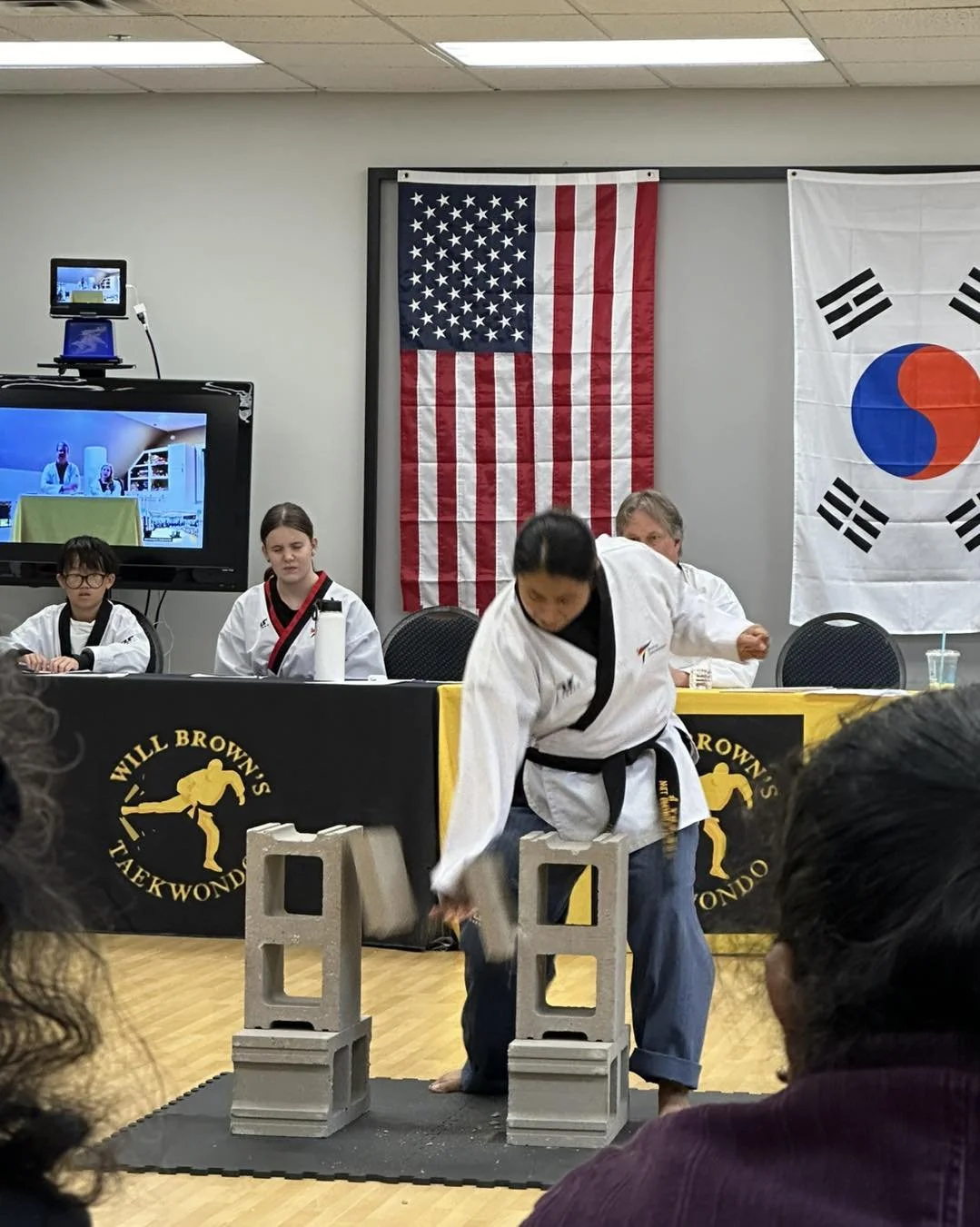 A student breaking concrete blocks during a belt testing demonstration at Will Brown's Taekwondo.
