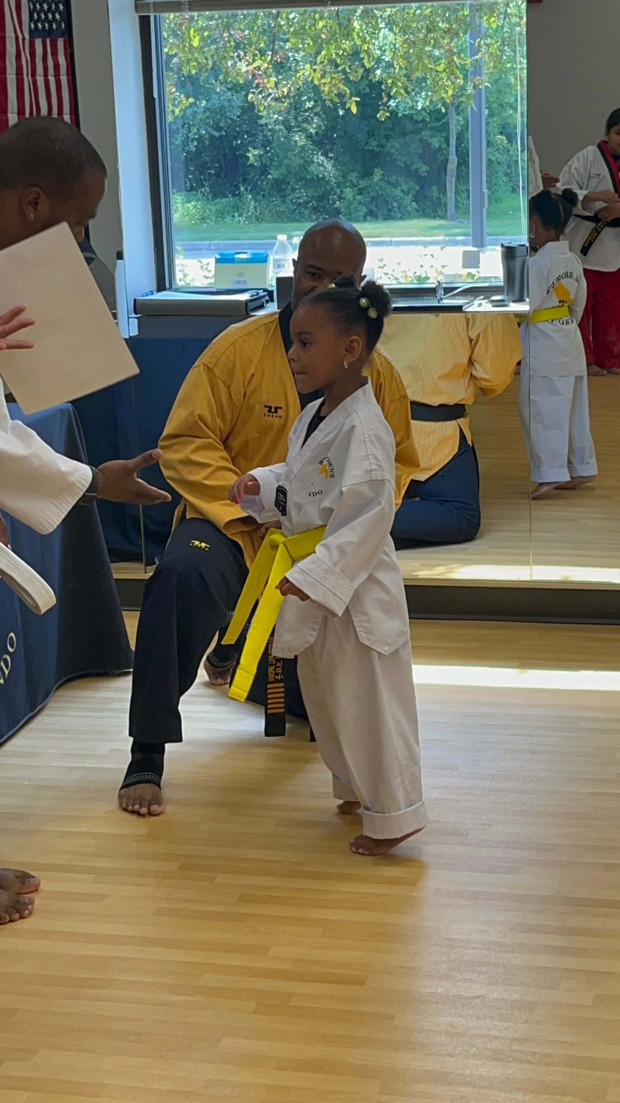  Master Will Brown watching as a young student receives her certificate for earning her gold belt. 
