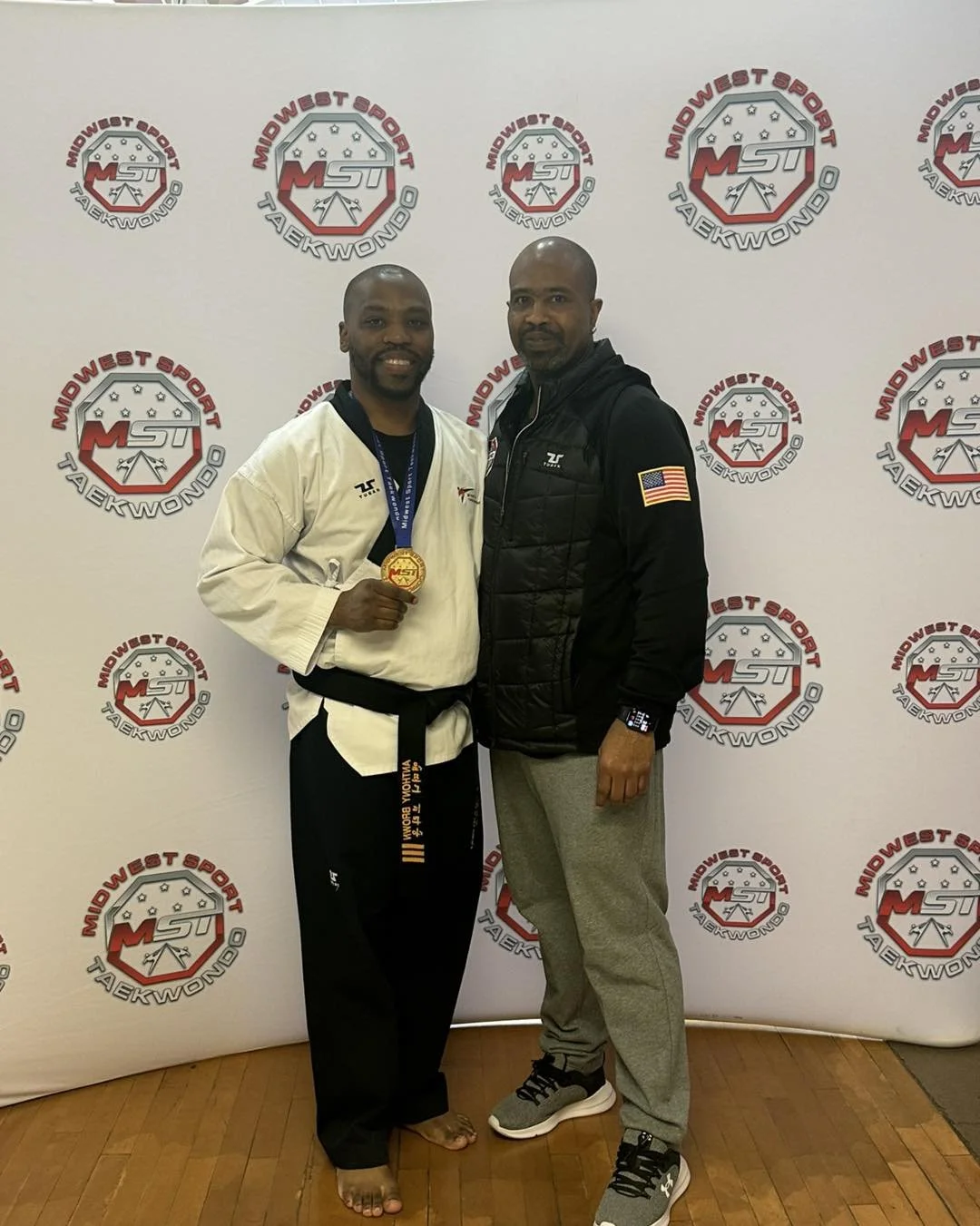 Assistant Instructor Anthony Brown proudly displaying his gold medal alongside Master Will Brown at a Midwest Sport Taekwondo tournament.