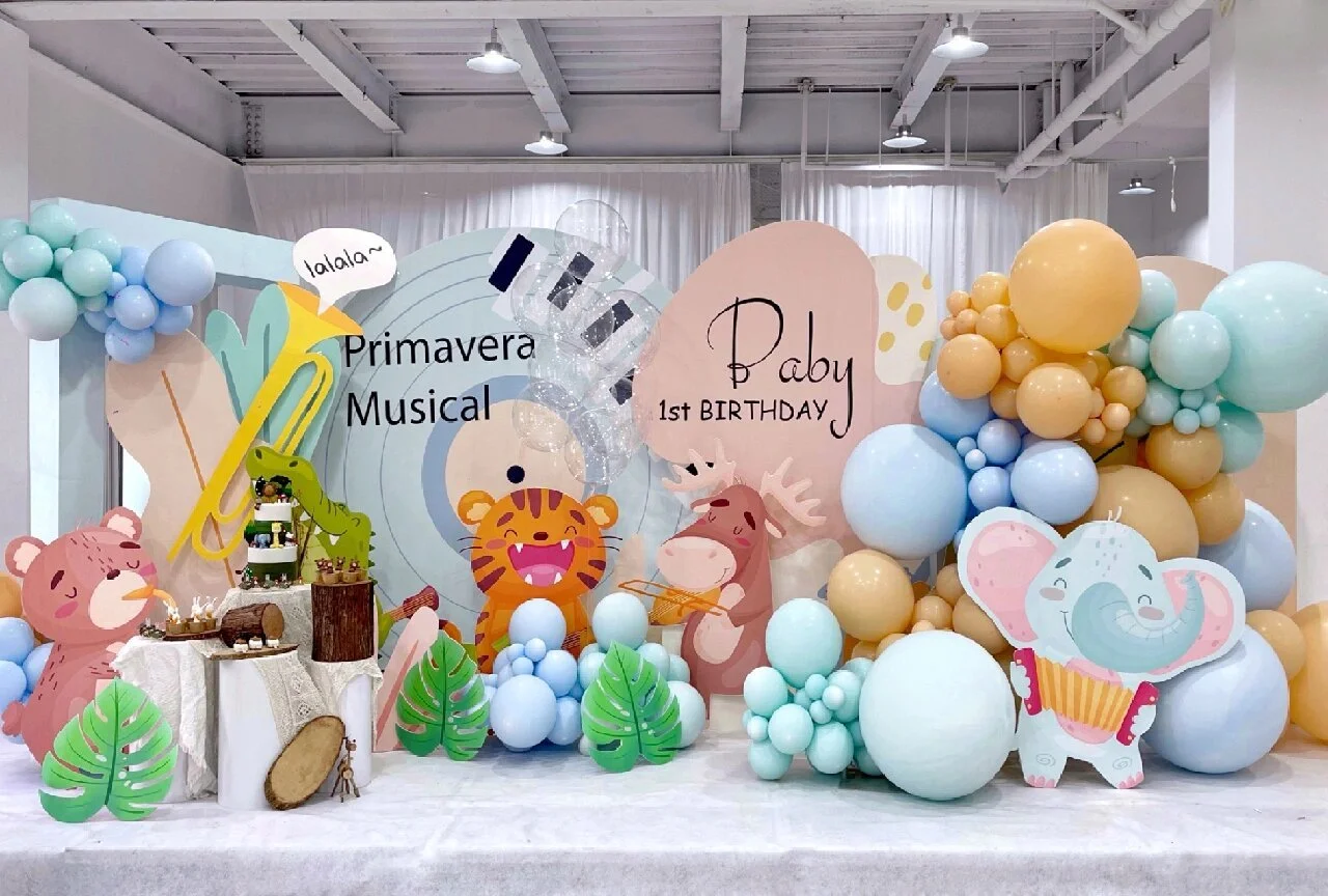 Decorations at a Memphis baby themed first birthday party with colorful balloons, cartoon animal cutouts including a lion, elephant, and deer, and a sign that says "Primavera Musical" and "Baby 1st BIRTHDAY".