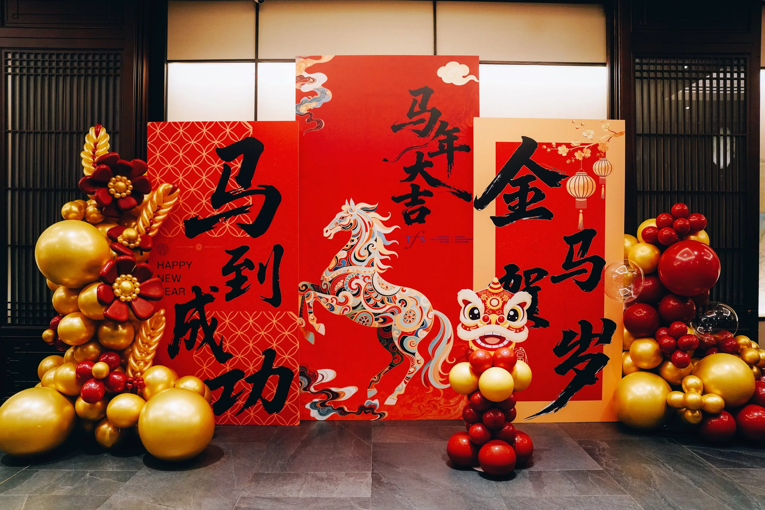 Decorative display celebrating Chinese New Year with red and gold balloons, traditional dragon and lion illustrations, and Chinese calligraphy.