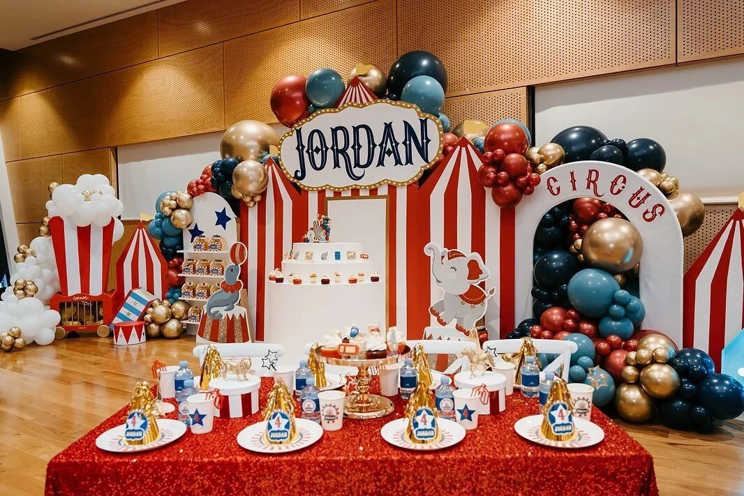 Circus-themed birthday party setup with balloons, a cake, and decorations featuring an elephant, a clown, and a carousel.