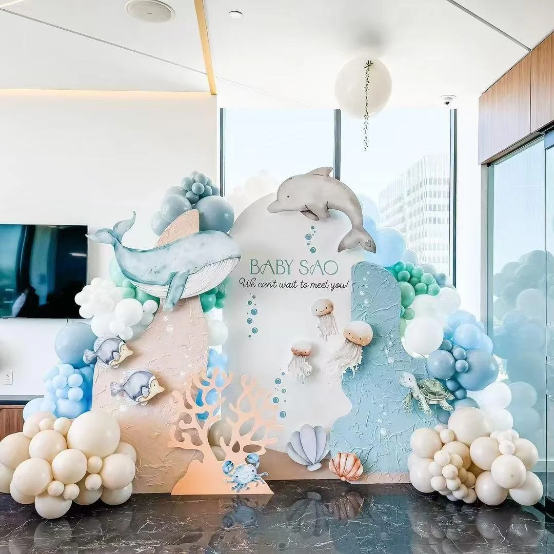 Underwater-themed baby shower decoration with whale, dolphin, fish, turtle, jellyfish, seashells, coral, and balloon arrangements in pastel colors. Center reads "BABY SAO We can't wait to meet you!"