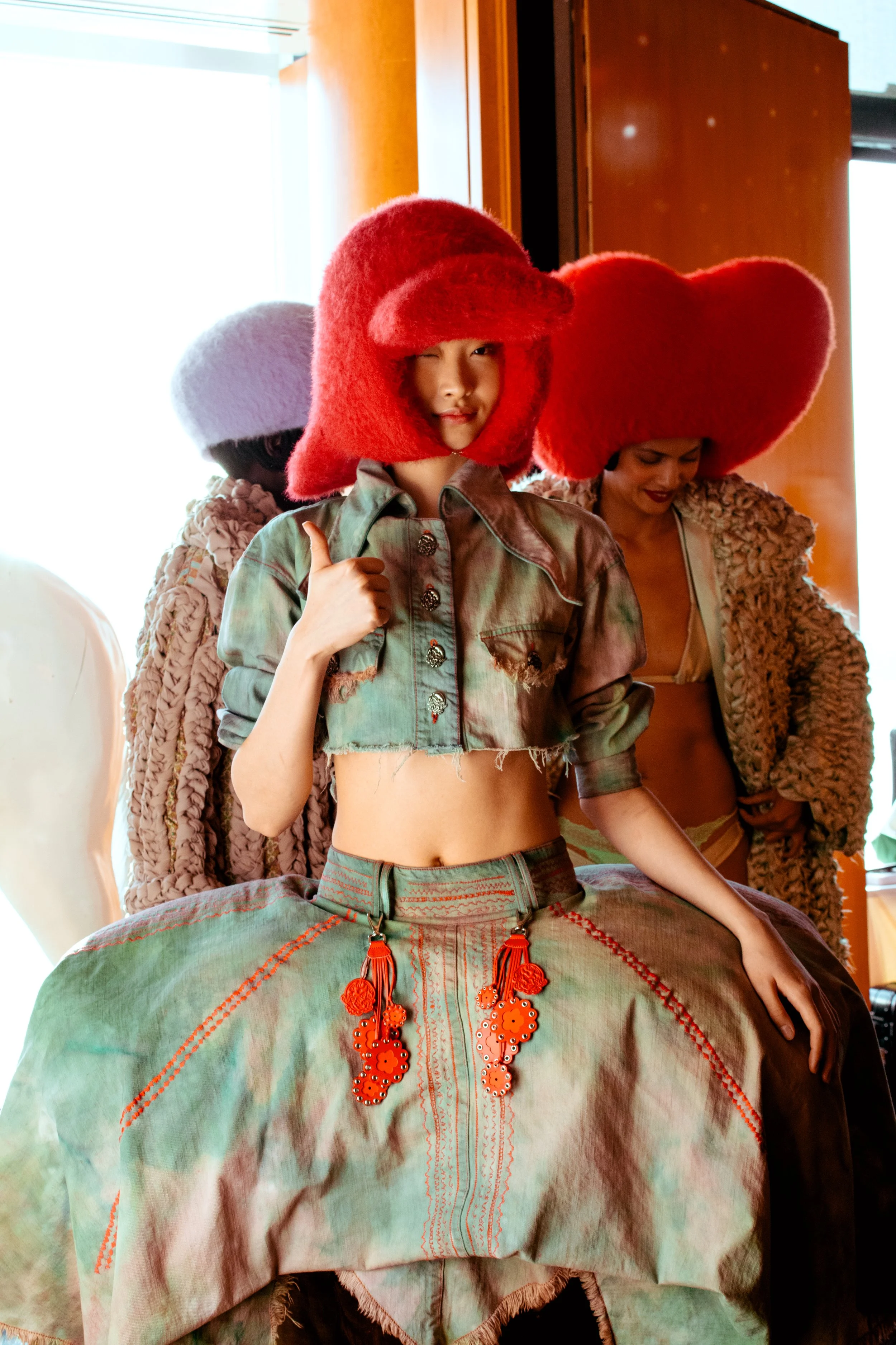 Women dressed in colorful, eclectic clothing with large, bold red hats.