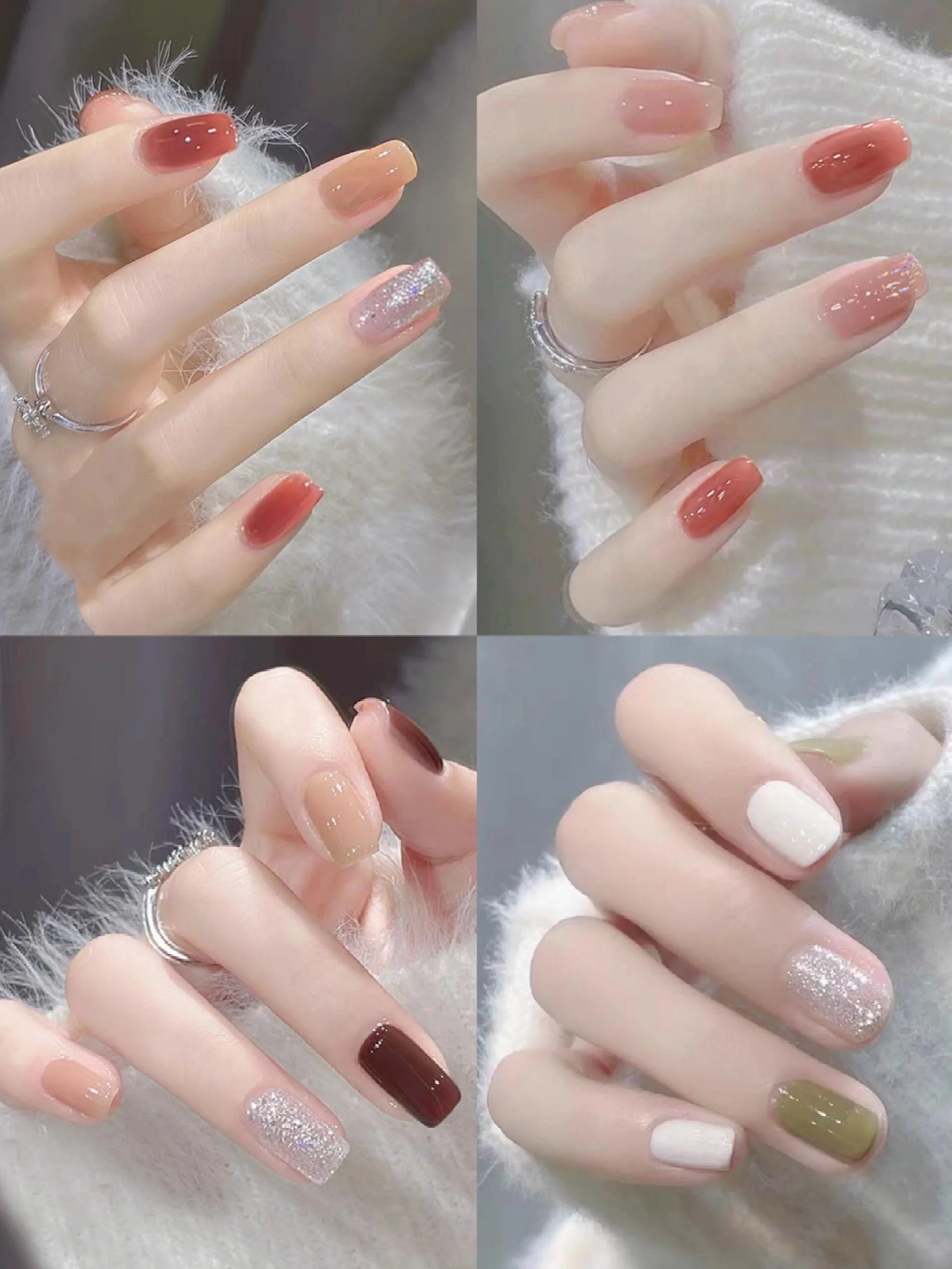Close-up of four hands with manicured nails in various styles and colors, wearing rings, against a fluffy white background.