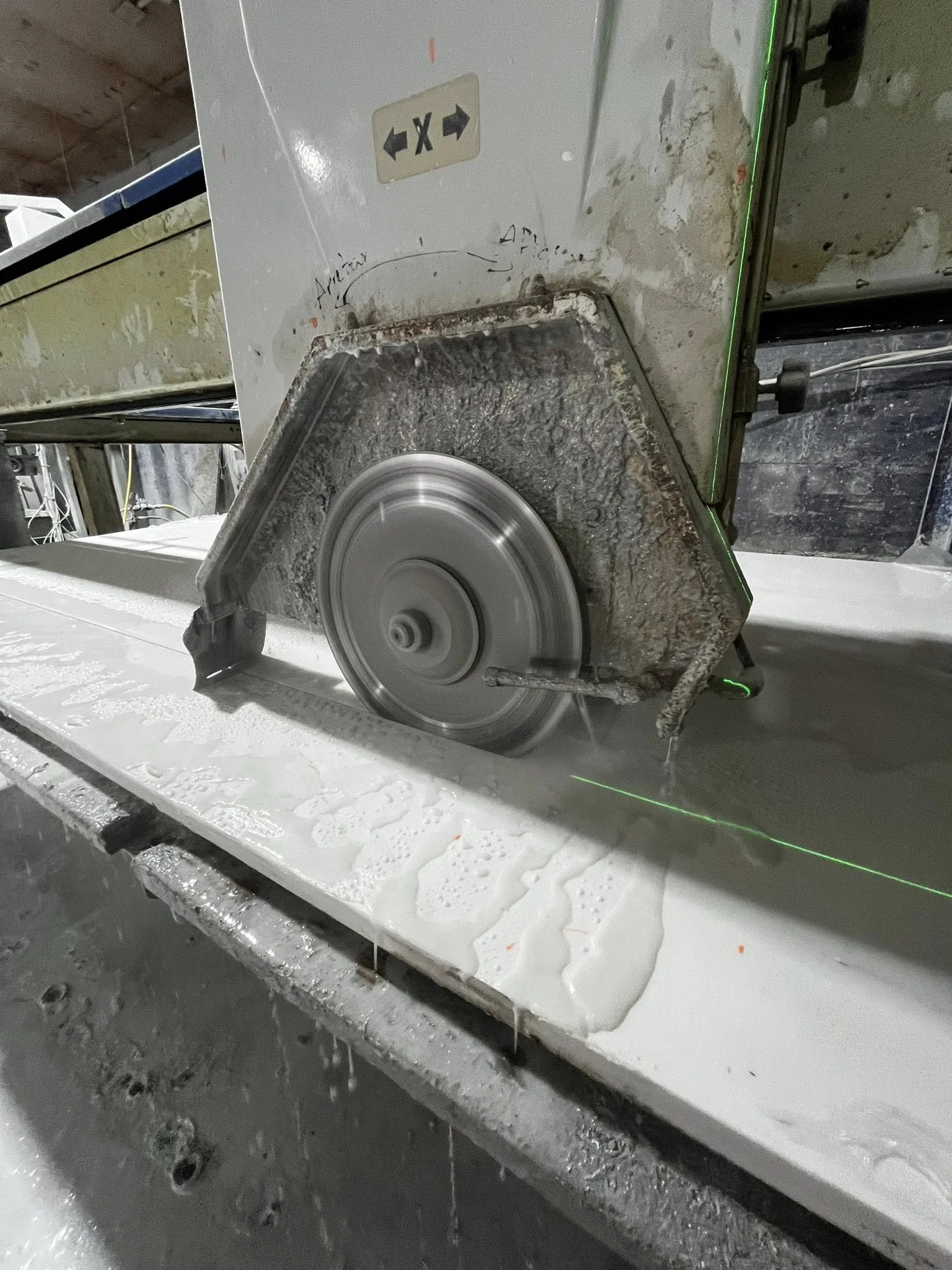Close-up of a CNC waterjet cutting machine cutting through material with a jet of water, with green laser lines visible.