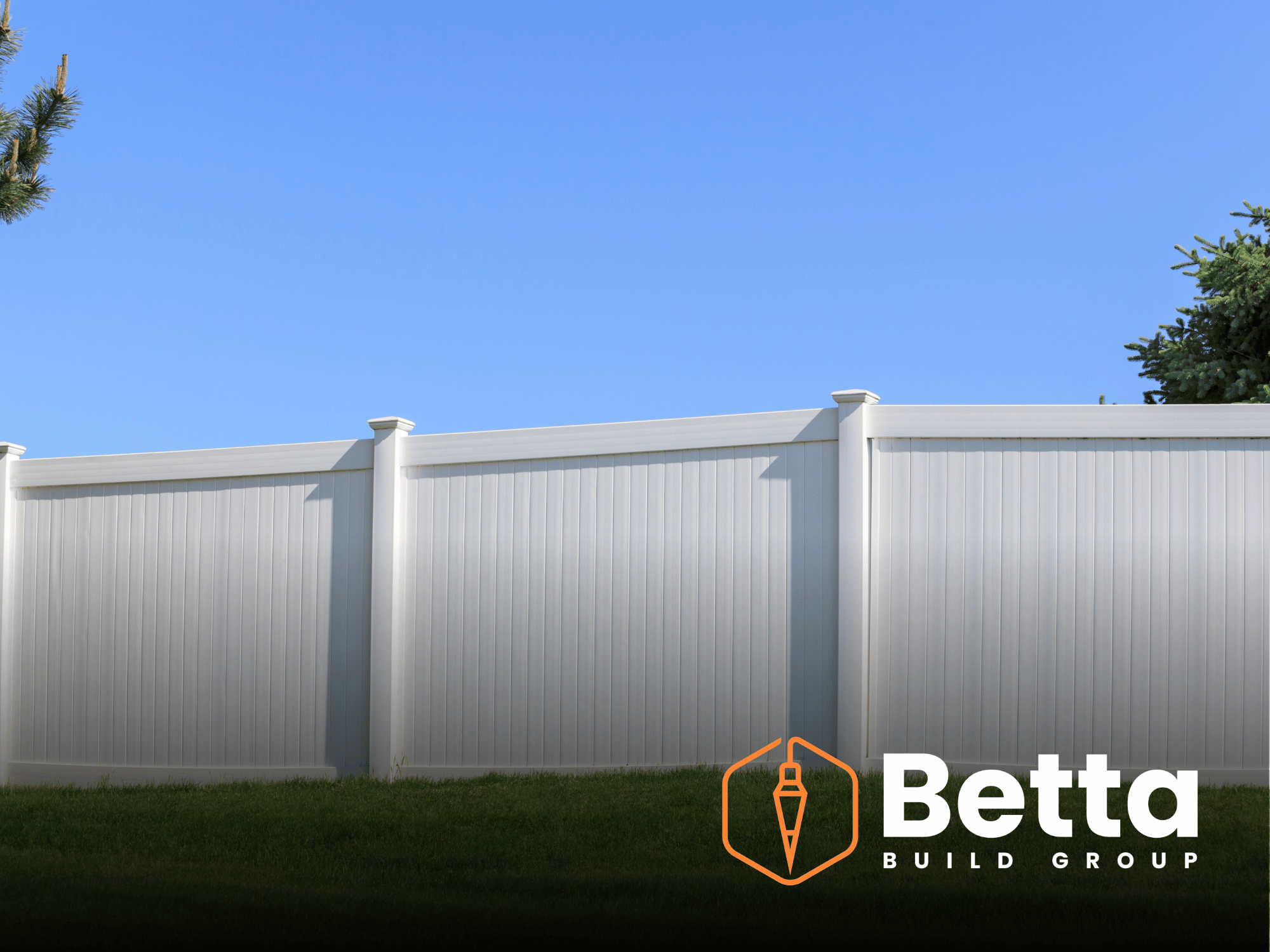 White privacy fence with green grass and trees in the background, under a bright blue sky.