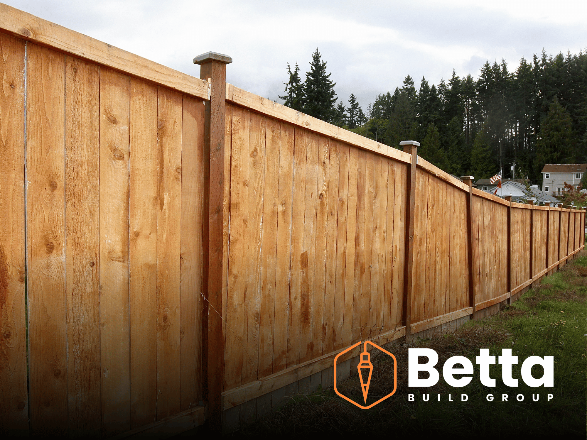 Photo of a newly built wooden privacy fence with vertical planks and horizontal top rail, set in a residential neighborhood with trees and houses in the background.