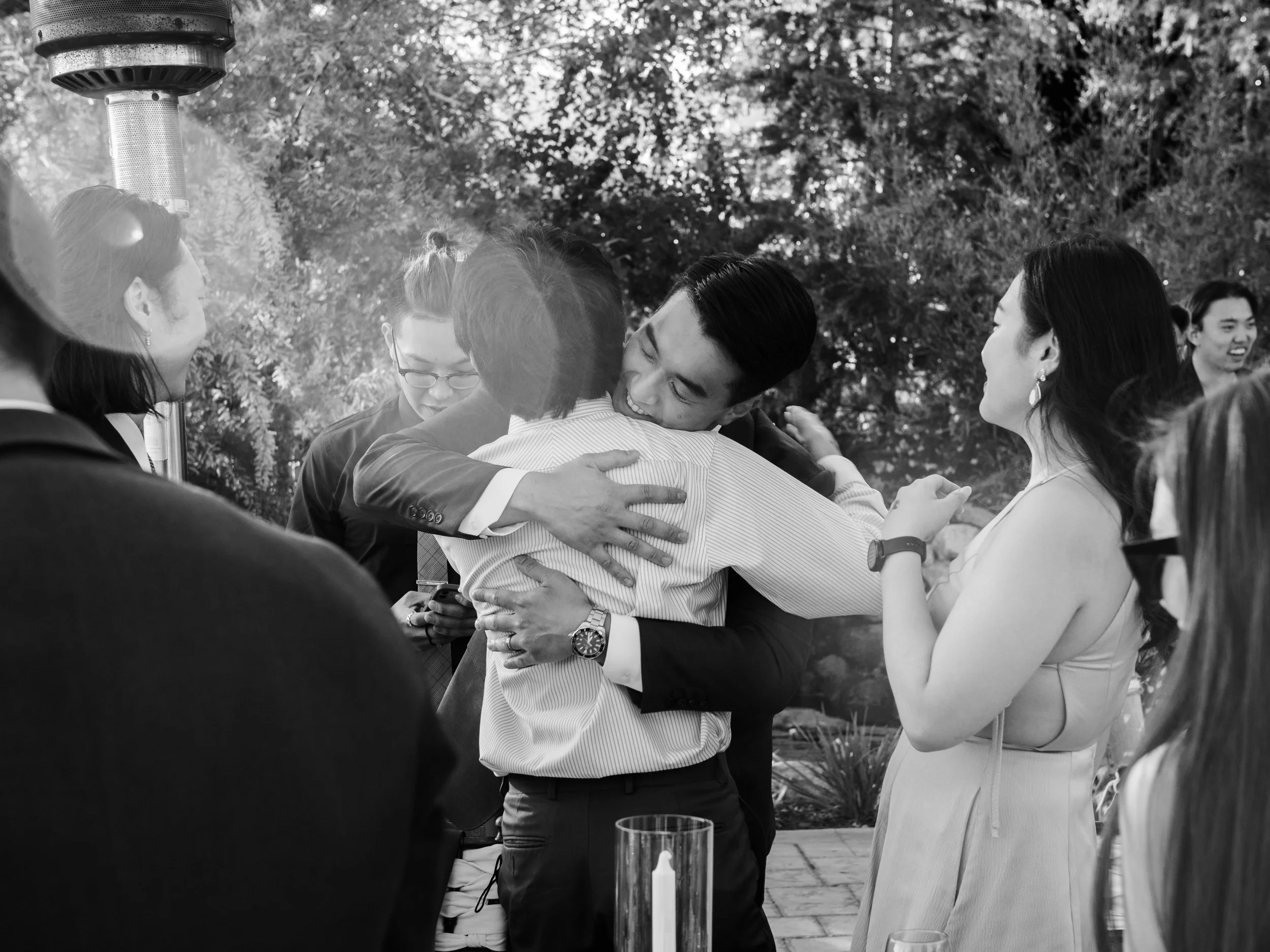 People hugging at an outdoor gathering.