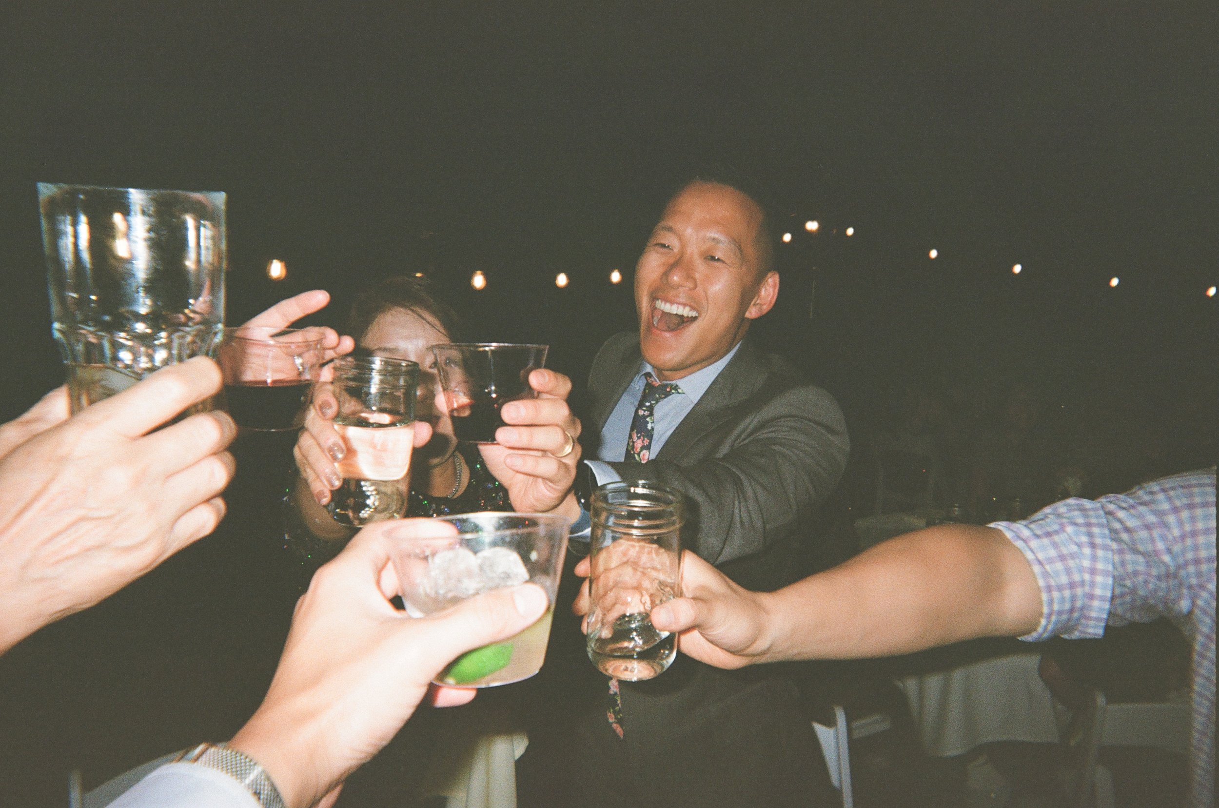 Group of people raising glasses for a toast at a party, smiling and celebrating.