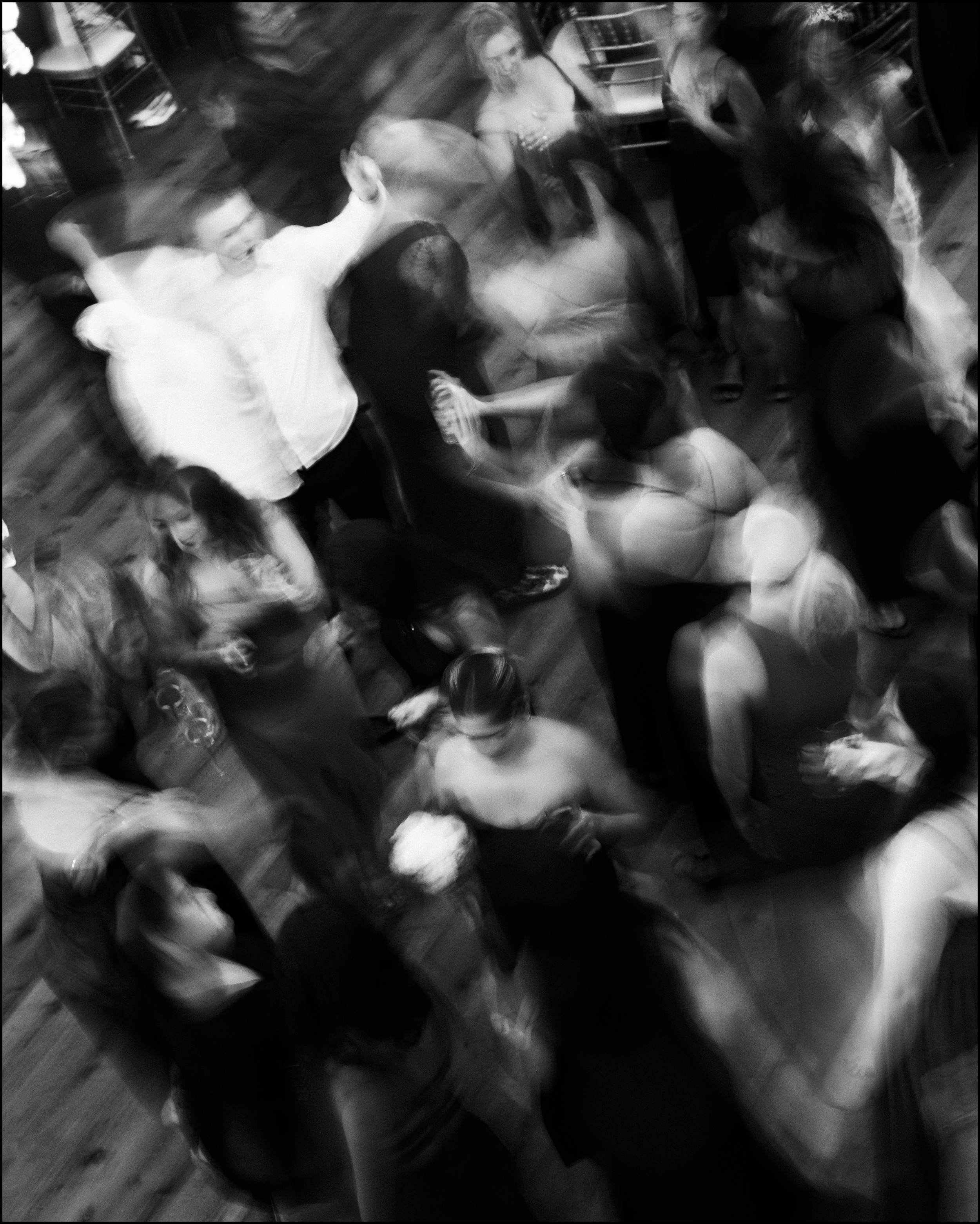 Black and white photo of a crowded dance floor with people dancing and socializing at an indoor event.