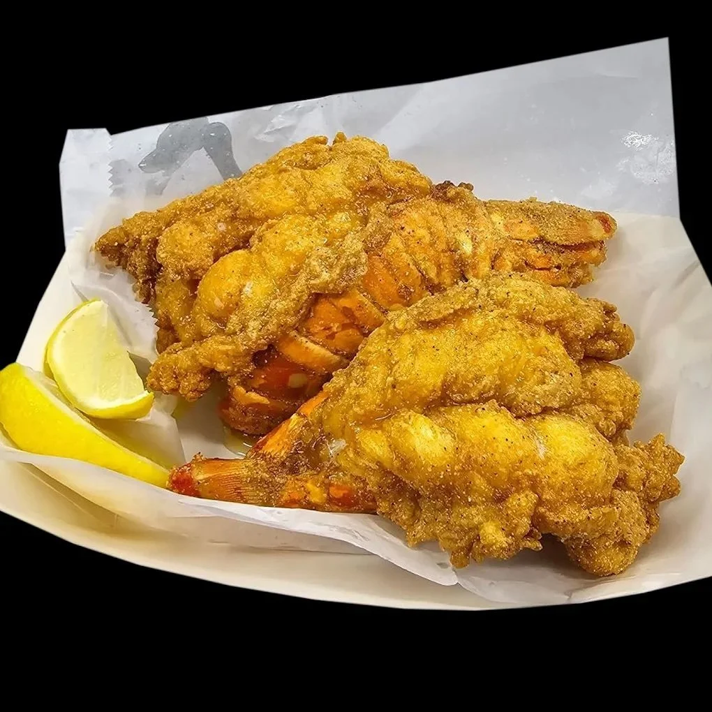 Two pieces of fried chicken and a lemon wedge on a paper-lined tray.