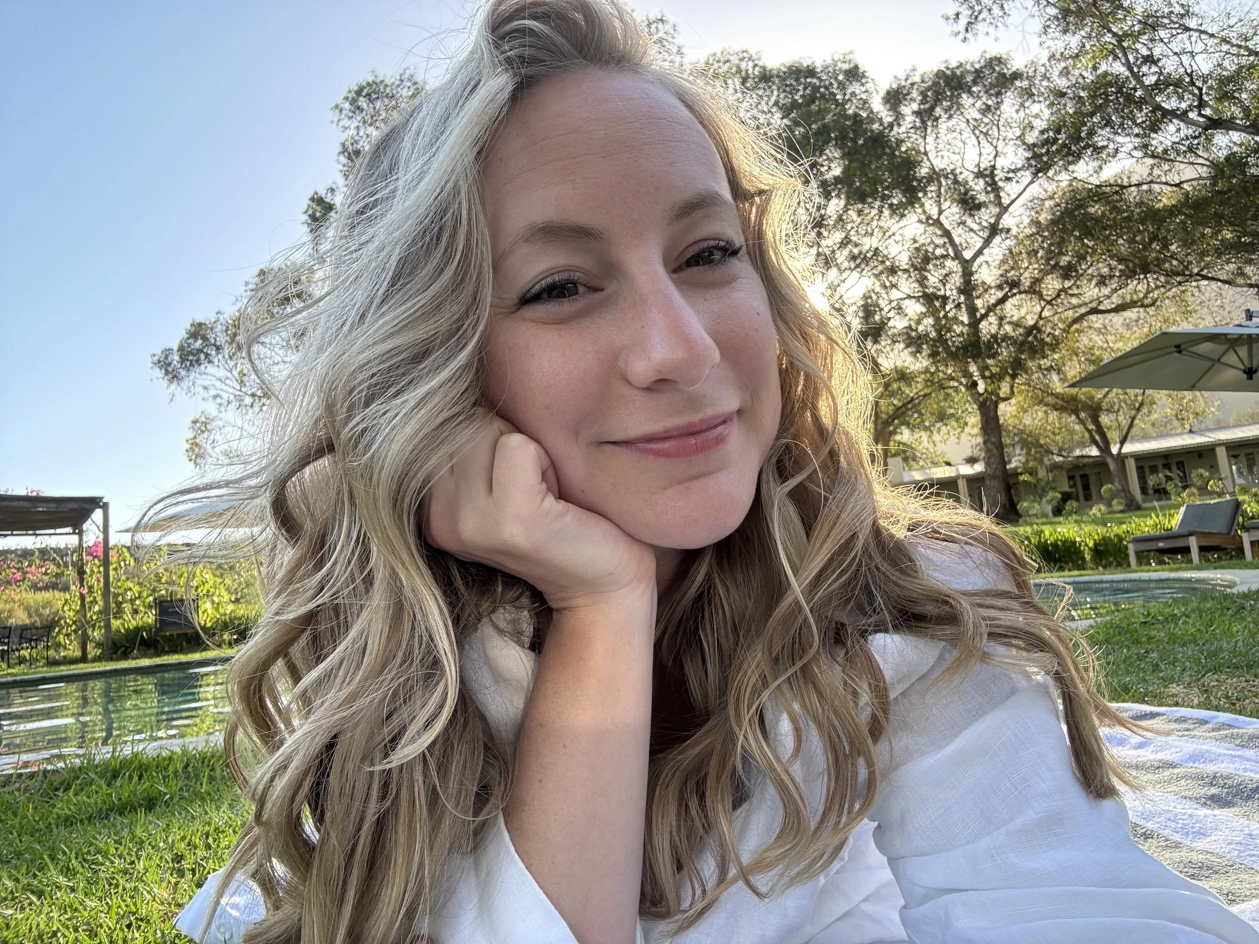 A full spectrum doula and founder of The Birth Atelier, Kirsten Vogt smiles with her hand on her chin.