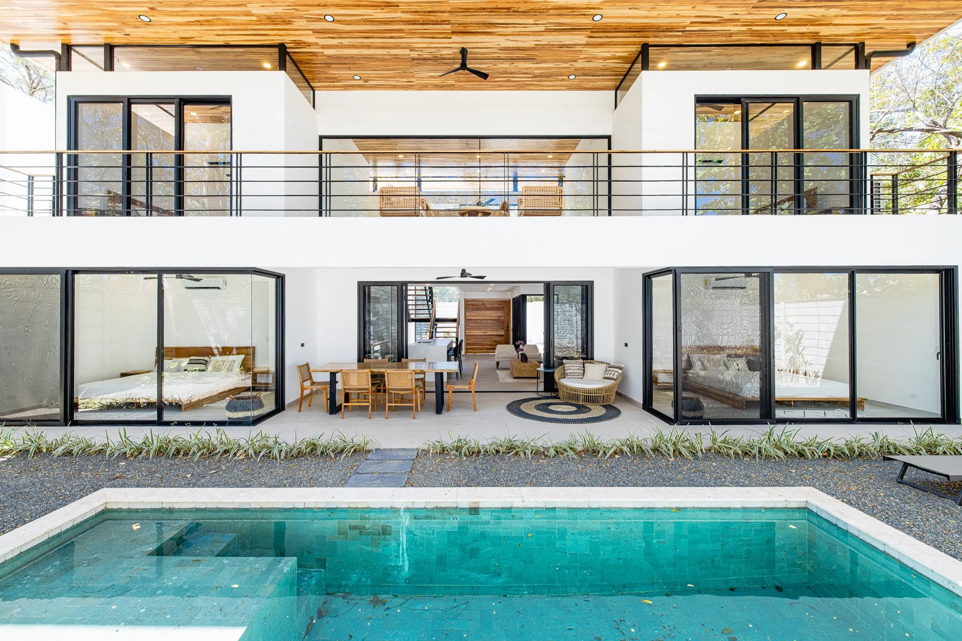 Modern house with glass sliding doors, outdoor sitting area, and a swimming pool in the backyard.